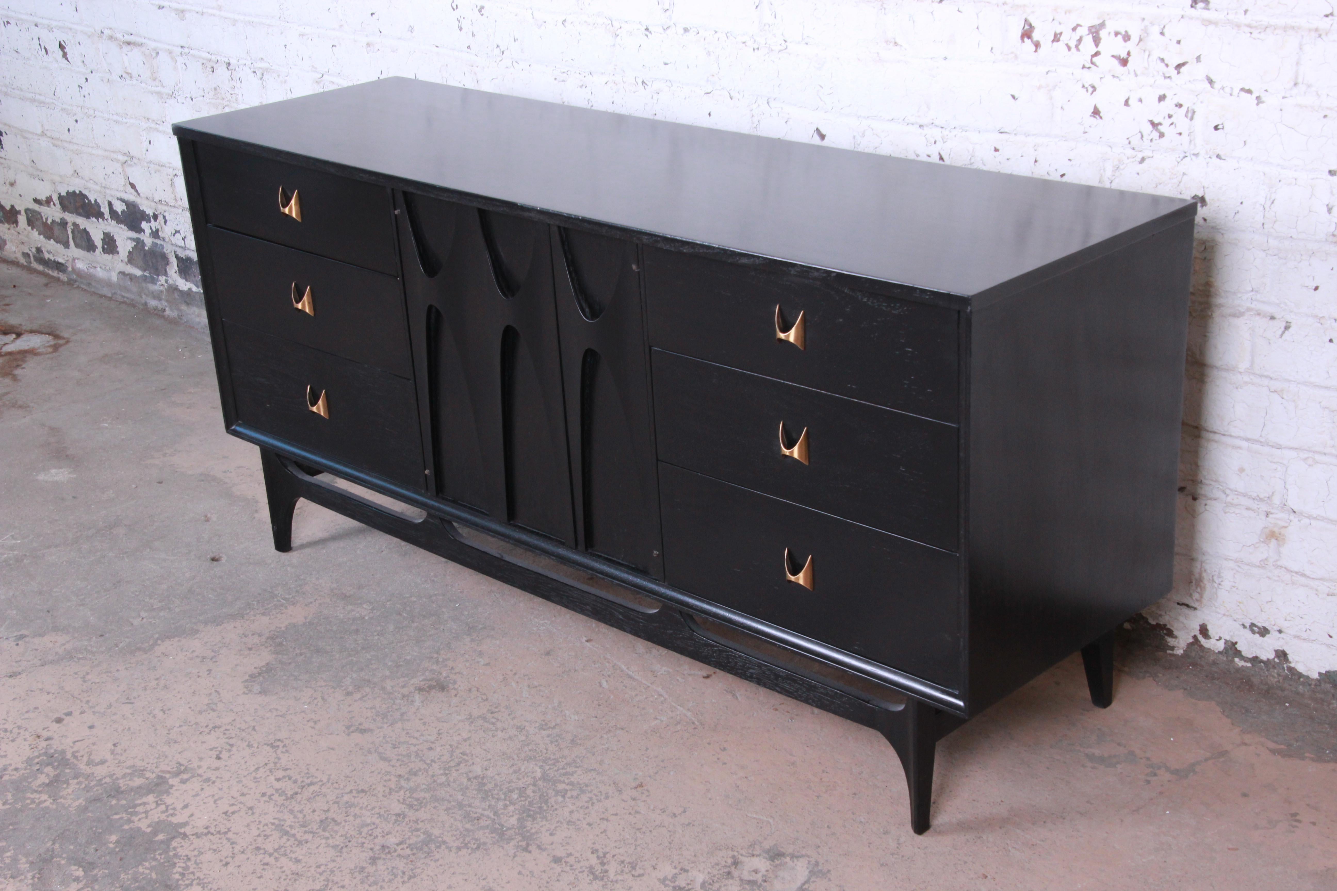Offering a gorgeous Mid-Century Modern long dresser or credenza by Broyhill Brasilia. The dresser features the iconic sculpted walnut design with newly ebonized finish and original sculpted arch brass pulls. It offers ample room for storage, with