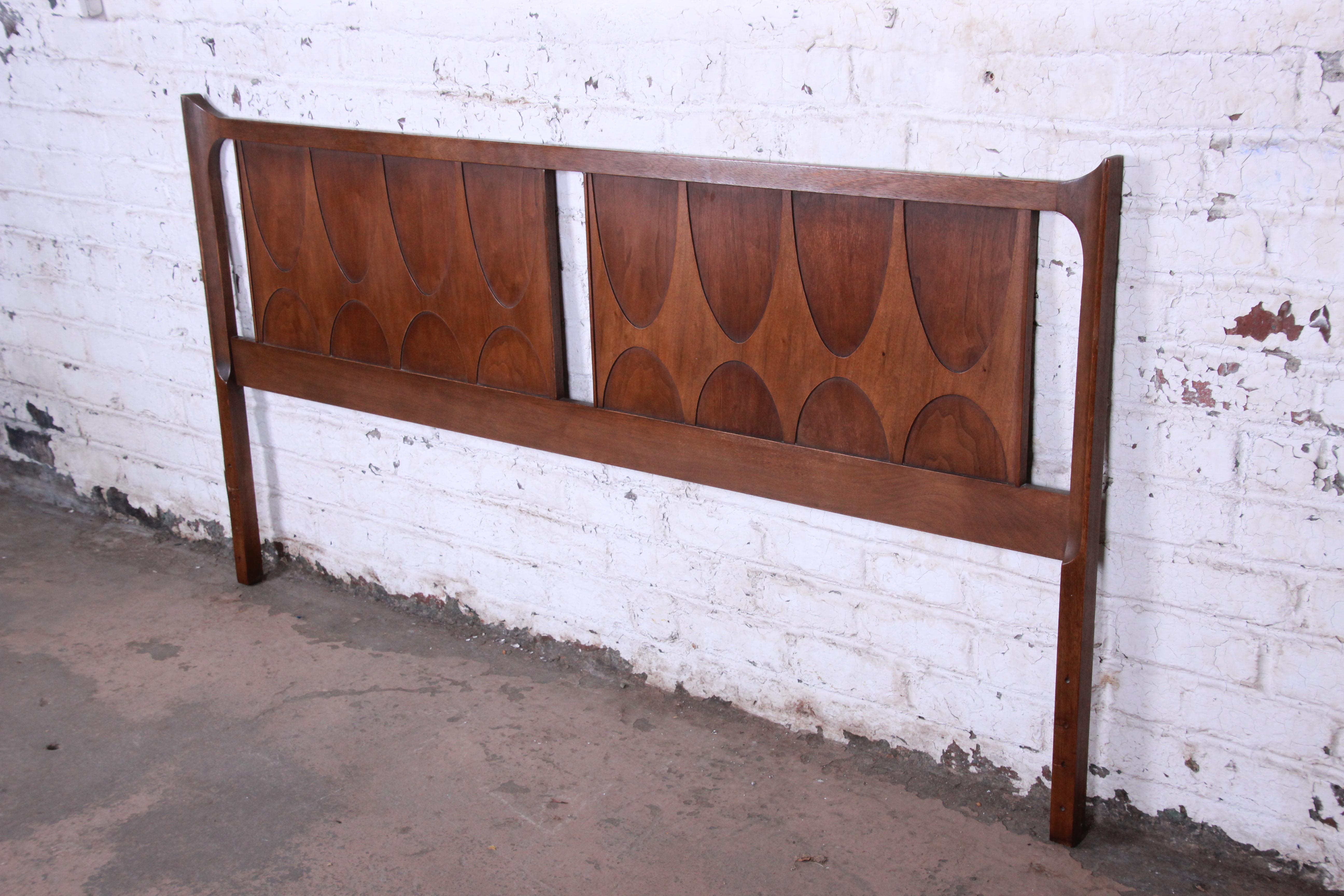 A gorgeous Mid-Century Modern sculpted walnut king size headboard by Broyhill Brasilia. The headboard features beautiful walnut wood grain and Classic Brasilia design. Rare to find this in a king size. The headboard is in very good original vintage