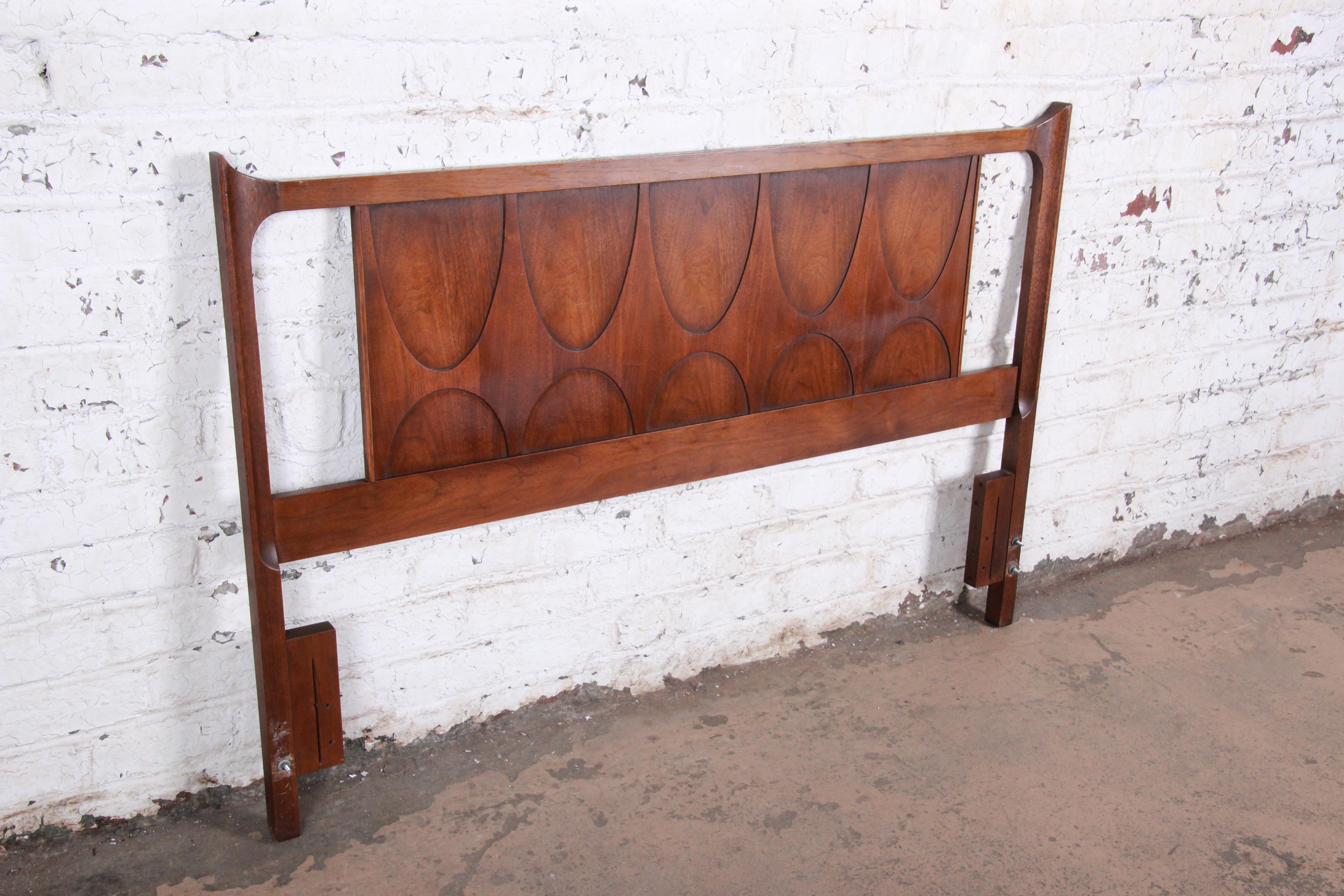 A stylish Mid-Century Modern sculpted walnut headboard by Broyhill Brasilia. The headboard features gorgeous walnut wood grain and the iconic arched Brasilia design. Works for both a queen or full size bed. The headboard is in very good original
