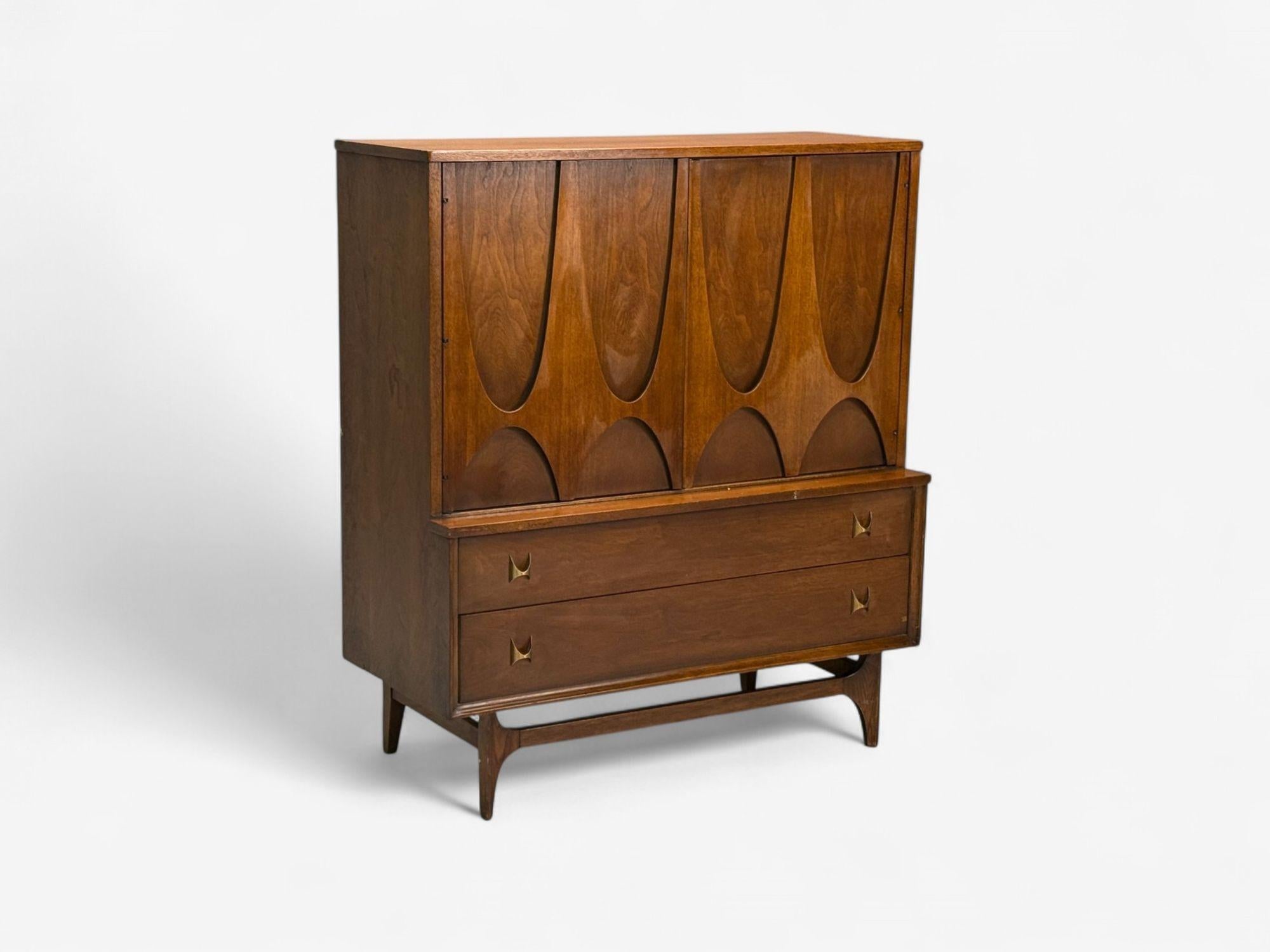 Broyhill Brasilia, Mid-Century Modern, Walnut, Brass, Highboy Dresser, USA, 1960s

Modernist highboy dresser designed and produced by Broyhill Brasilia in the United States circa 1960s. This example features a brutalist style carved walnut upper