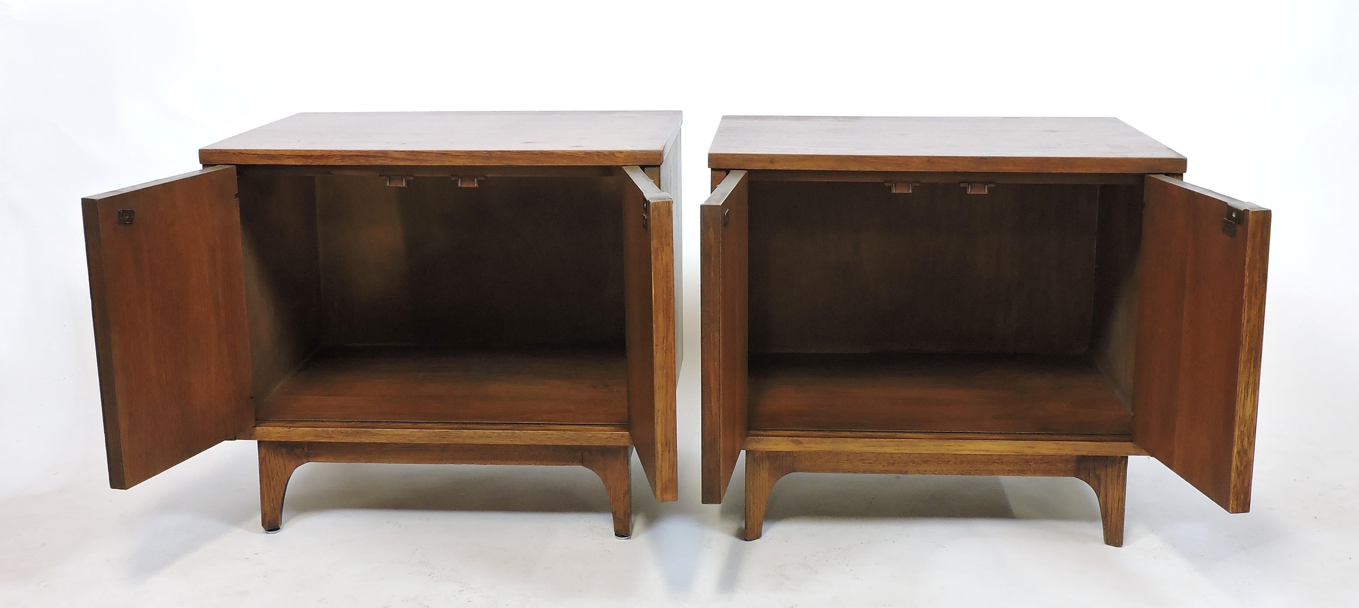 Pair of distinctive walnut nightstands which was part of Broyhill's Brasilia line that was inspired by Oscar Niemeyers Mid-Century Modern Brazilian architecture. These nightstands have two doors with arched details that open up to a large space for