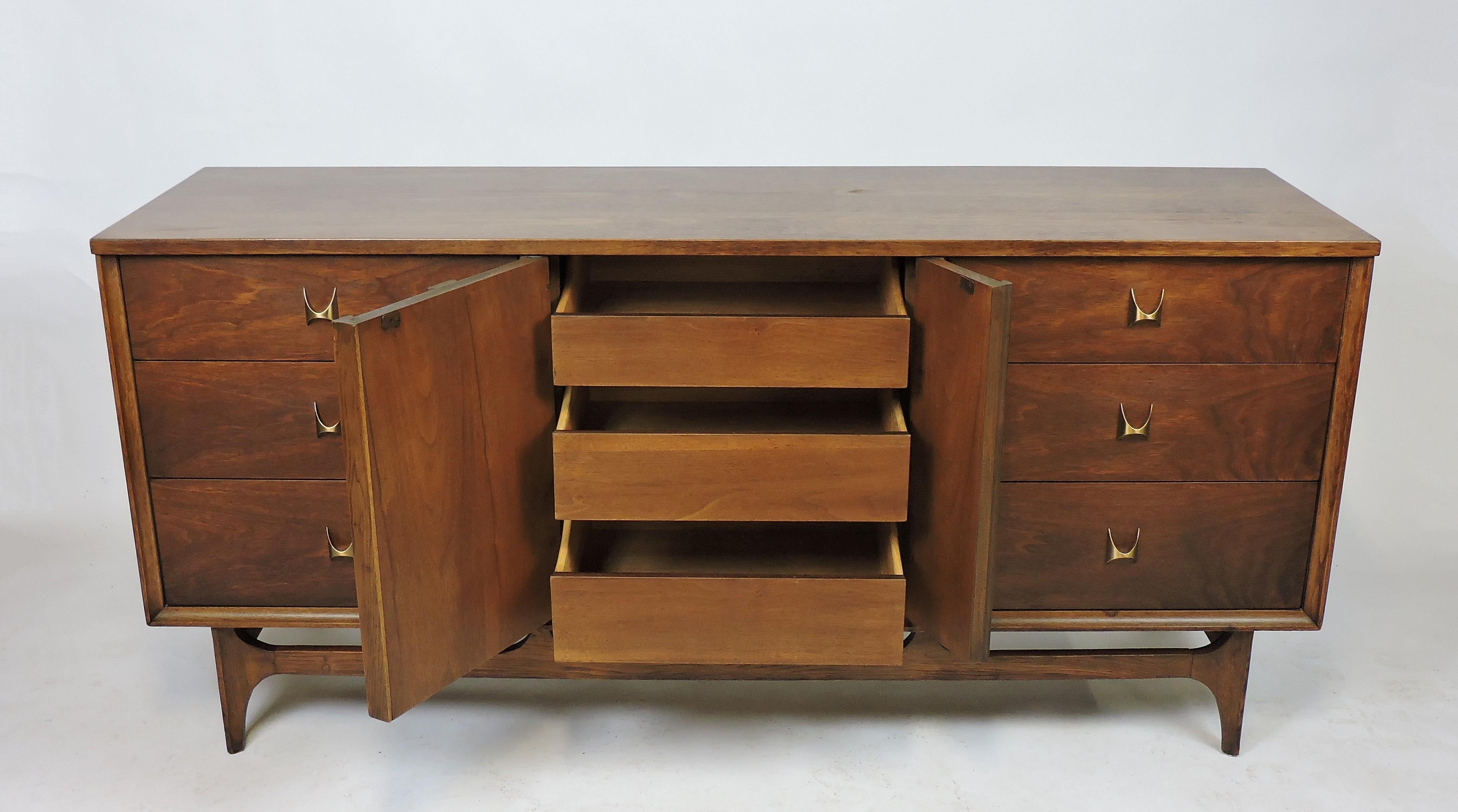 Distinctive walnut nine-drawer triple dresser which was part Broyhill's Brasilia line that was inspired by Oscar Niemeyers mid century Brazilian architecture. This cabinet has lots of storage with six large drawers and three concealed smaller ones.