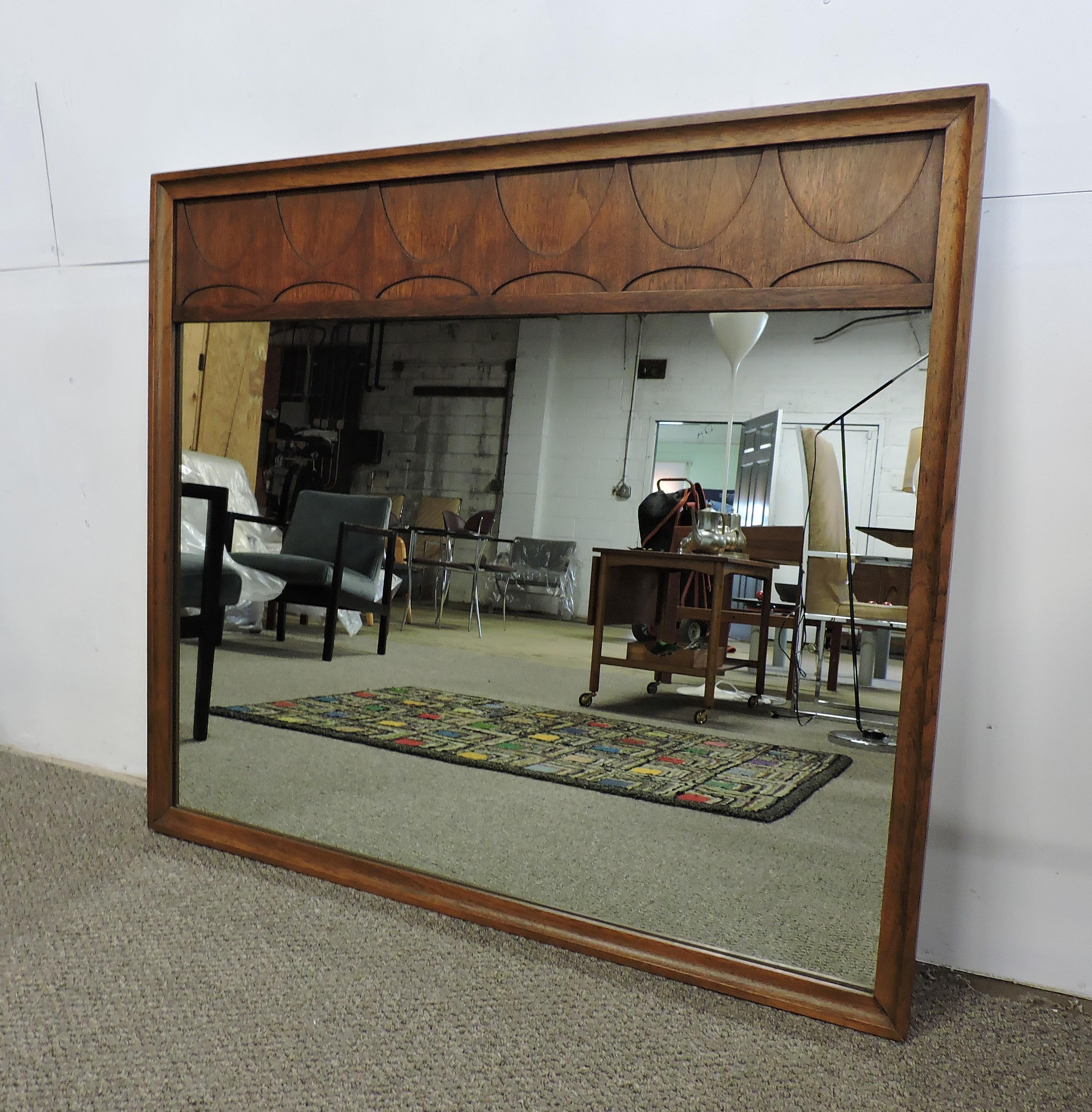 Distinctive large and substantial walnut mirror which was part of Broyhill's Brasilia line that was inspired by Oscar Niemeyers Mid-Century Modern Brazilian architecture. This mirror has a walnut frame with arched details. Stamped on the back with