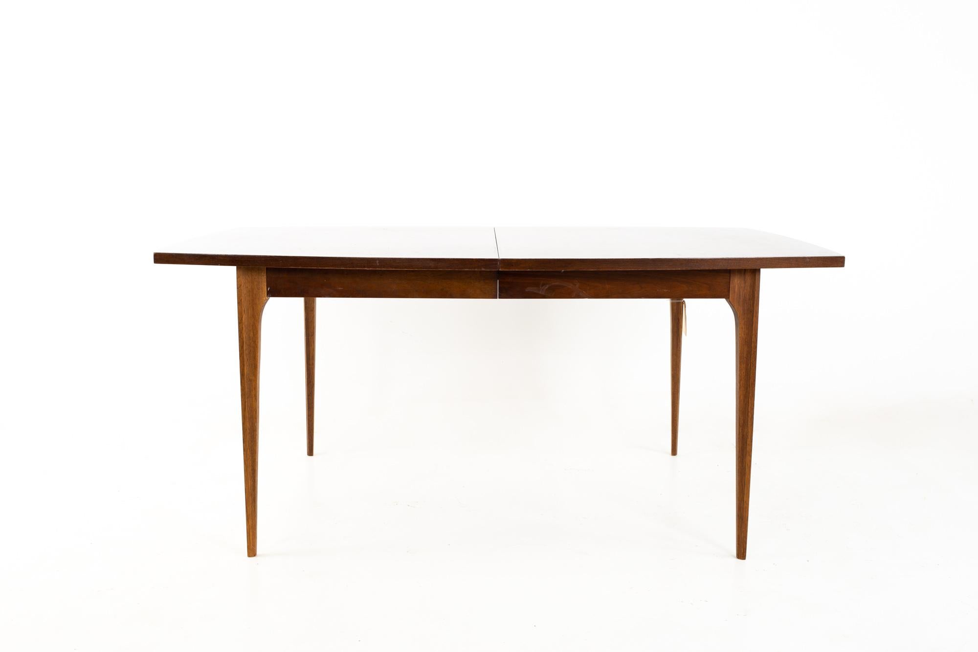 Broyhill Brasilia mid century walnut surfboard dining table.
Table measures: 66 wide x 40 deep x 30 high, with a chair clearance of 26 inches; each leaf is 12 inches wide, making a maximum table width of 90 inches when both leaves are used

All