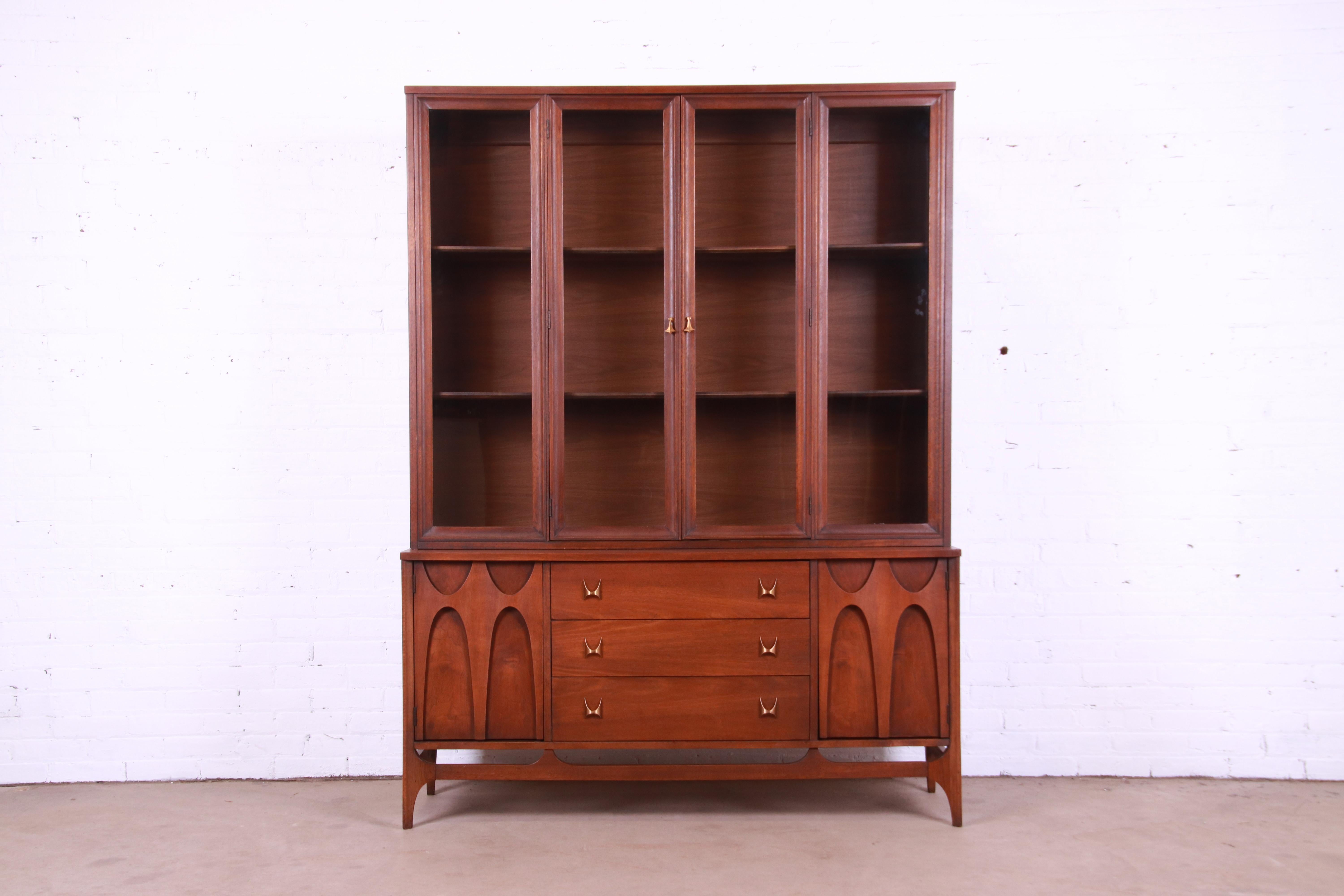 An exceptional Mid-Century Modern breakfront bookcase cabinet or sideboard with hutch top

By Broyhill Brasilia

USA, 1960s

Sculpted walnut, with iconic brass arch drawer pulls and glass front doors.

Measures: 56