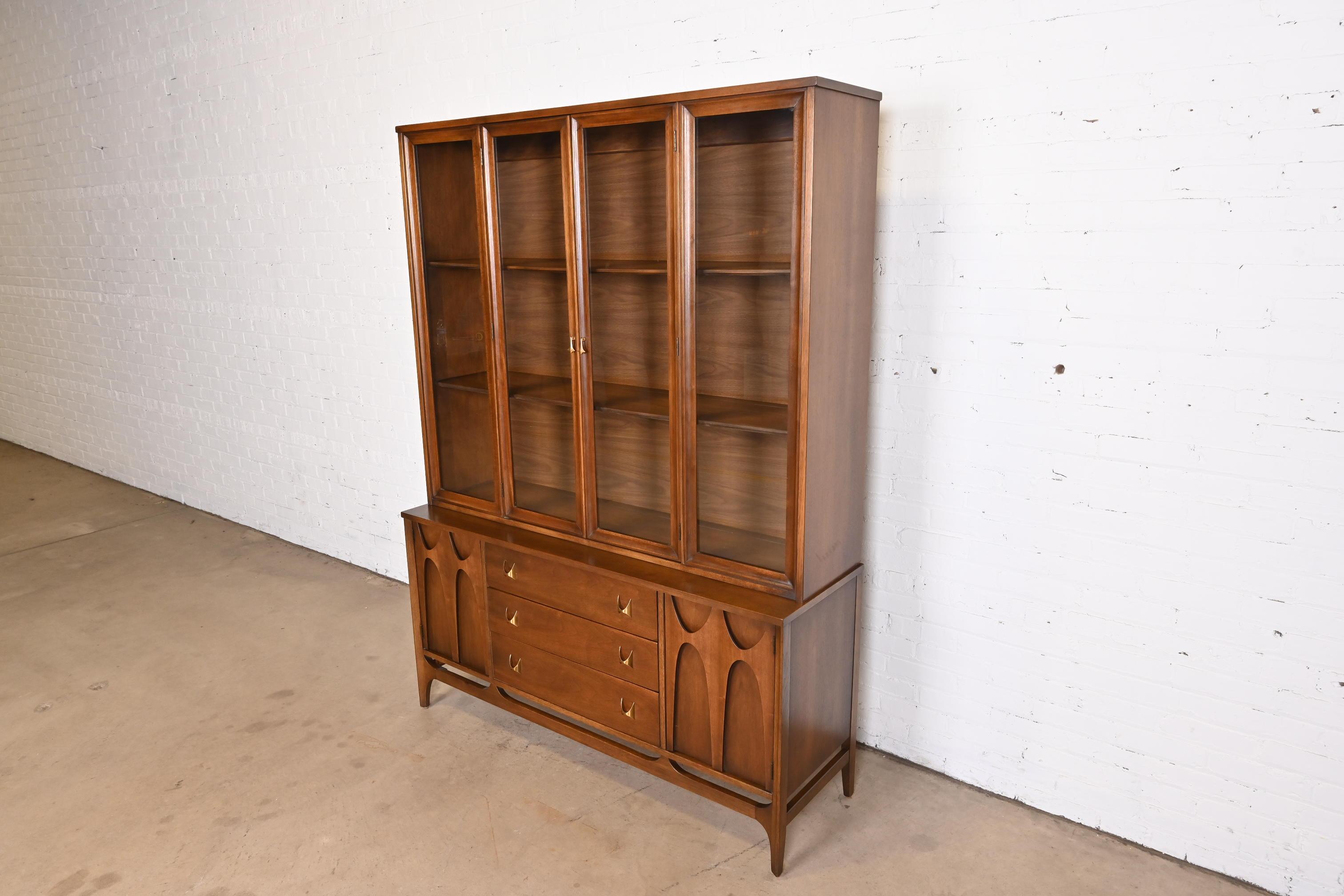 An exceptional Mid-Century Modern breakfront bookcase cabinet or sideboard with hutch top

By Broyhill Brasilia

USA, 1960s

Sculpted walnut, with iconic brass arch drawer pulls and glass front doors.

Measures: 56