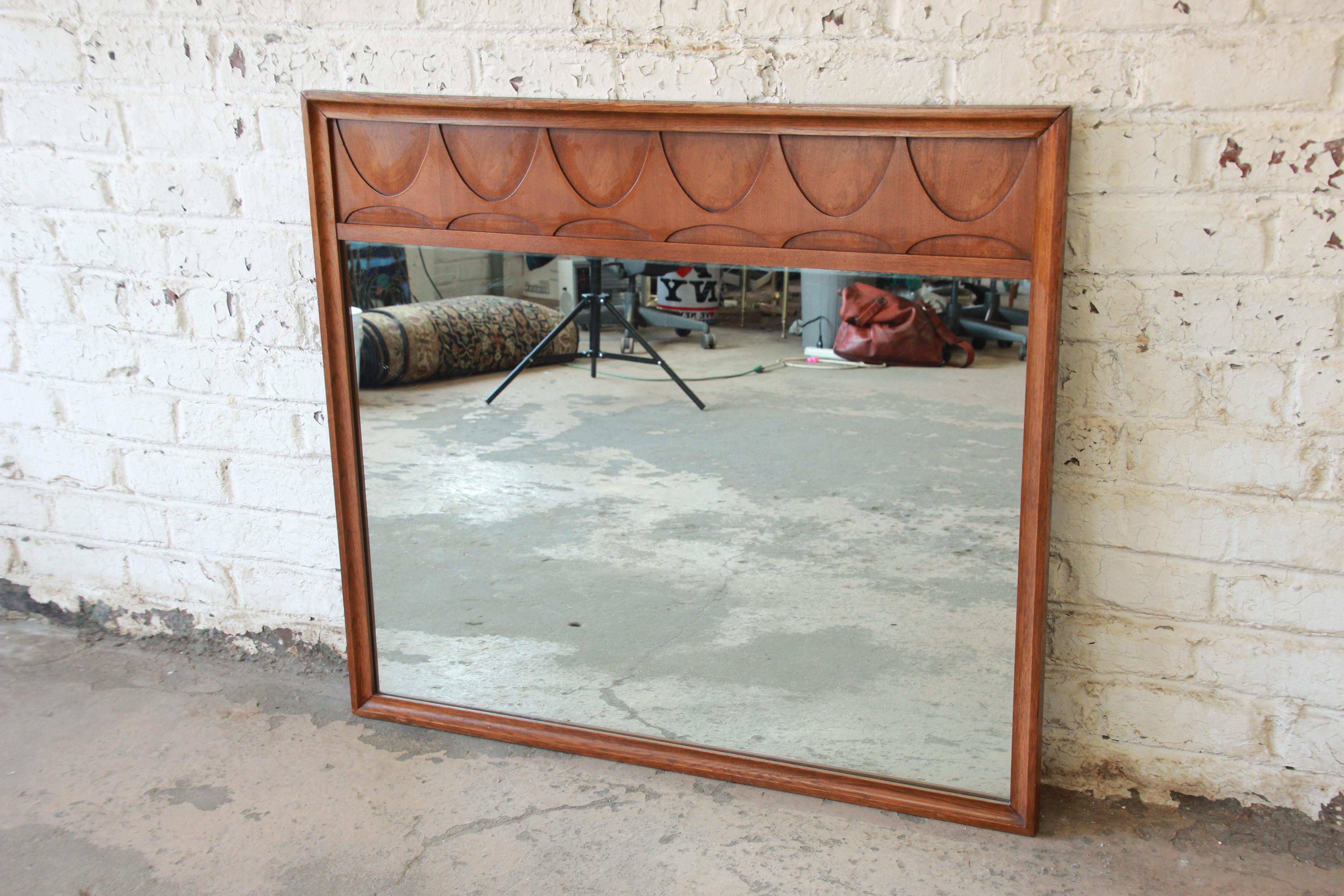 Offering a very nice Broyhill Brasilia sculpted walnut Mid-Century Modern mirror. The mirror has a nice walnut wood frame. The mirror is in good vintage condition with wear to the surface of the top of the mirror.
