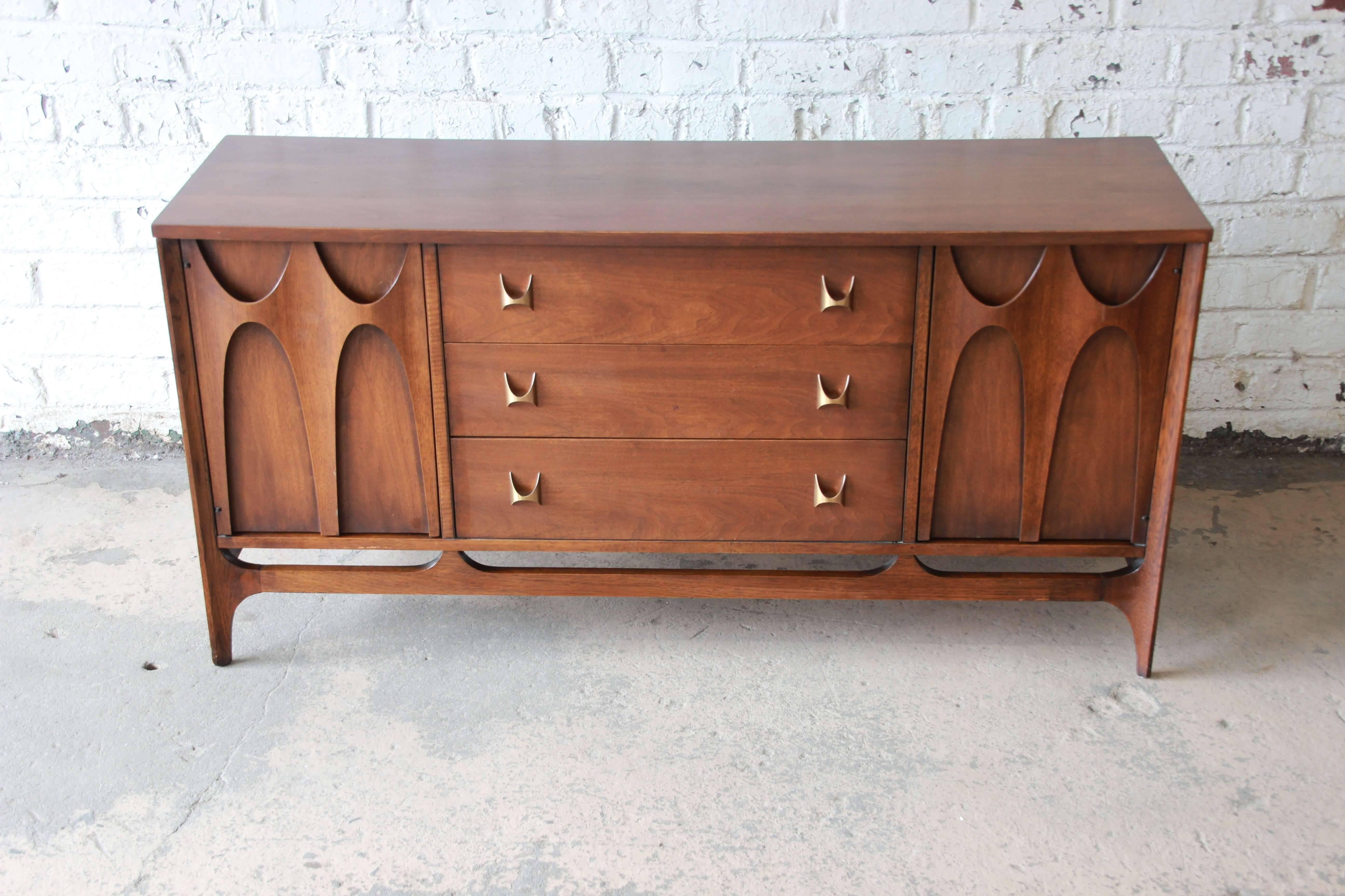 Offering a very nice and iconic Mid-Century Modern Broyhill Brasilia sideboard credenza. The credenza has sculpted walnut pulls on the two outside cabinets that open up to a shelf for storage. The centre offer three drawers for additional storage.
