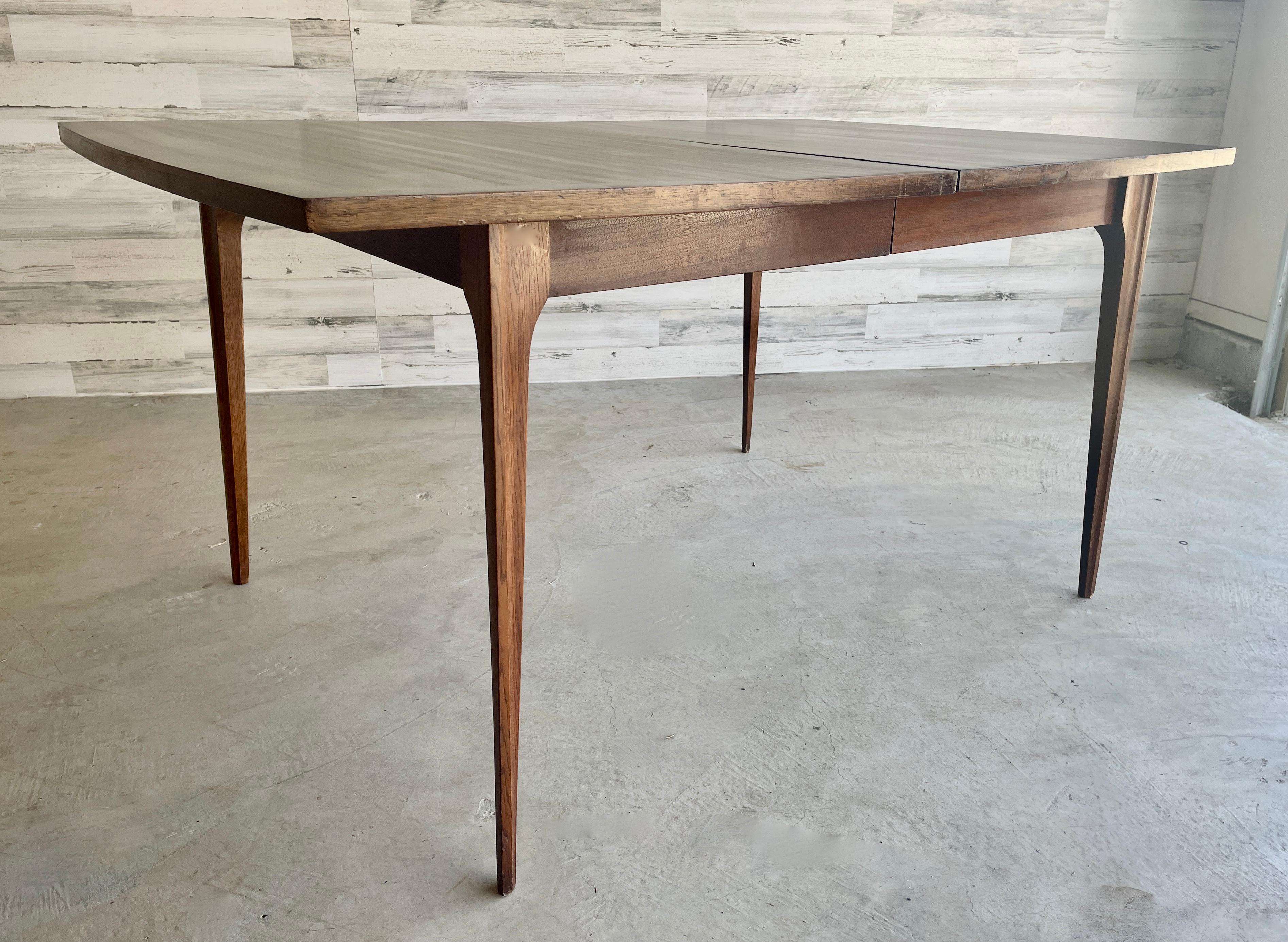 Broyhill Brasilia walnut extendable dining table with one leaf. A truly iconic design for any Mid century home. Length with leaf: 72 L.