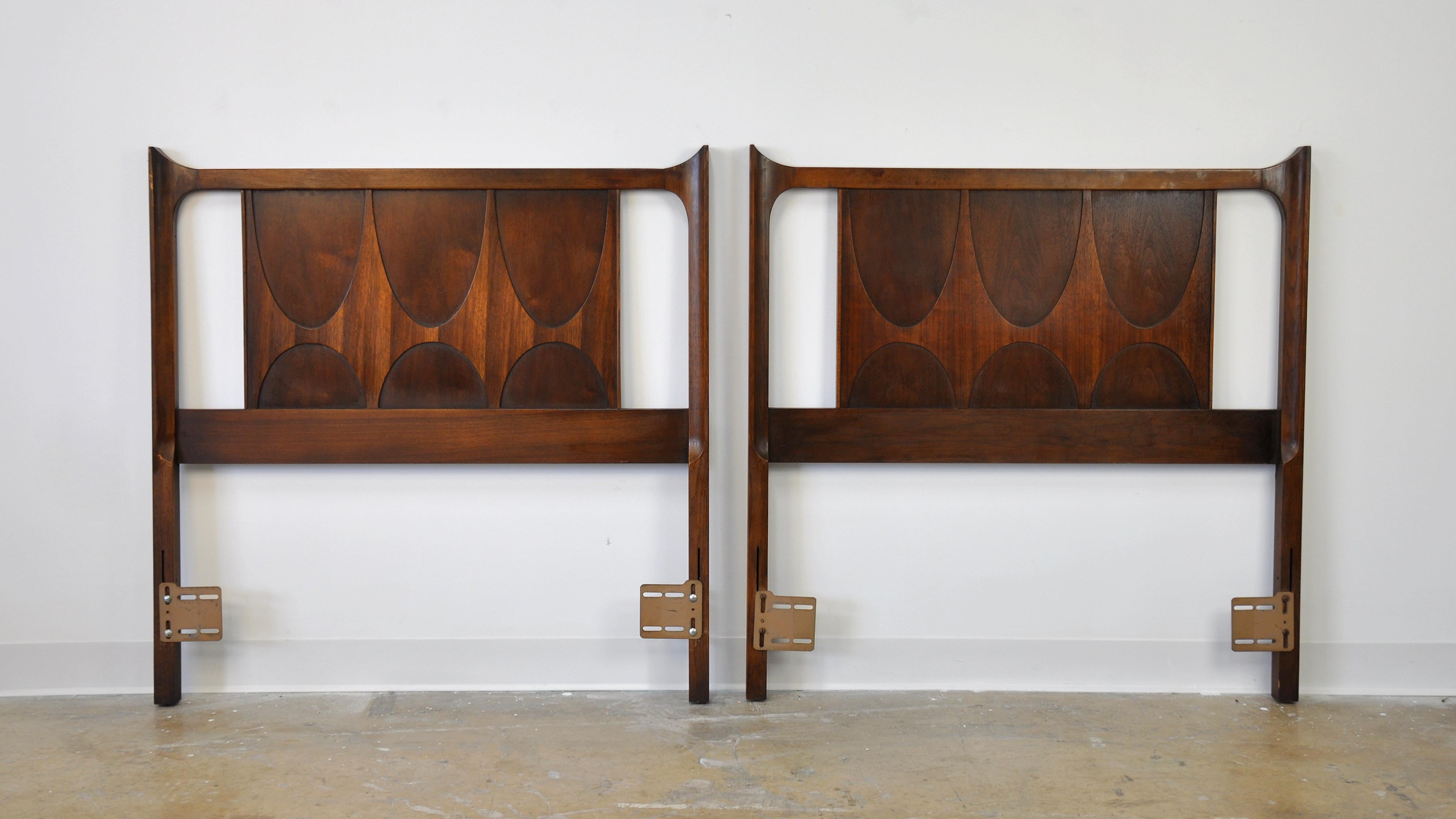 A vintage Mid-Century Modern pair of twin headboards that, if placed together, can be used with a king size bed. Manufactured by Broyhill in the 1960s, each solid walnut frame features the signature relief cut and sculpted pattern modeled after