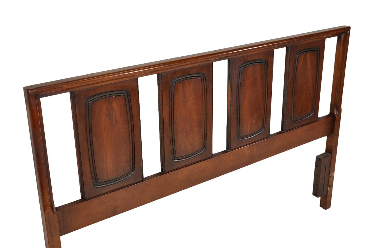 A vintage Mid-Century Modern queen size walnut bed dating from the 1960s manufactured by Broyhill for their Emphasis collection. The sculptural bed frame features framed panels with beautiful wood grain and is solid walnut. Its simple aesthetic
