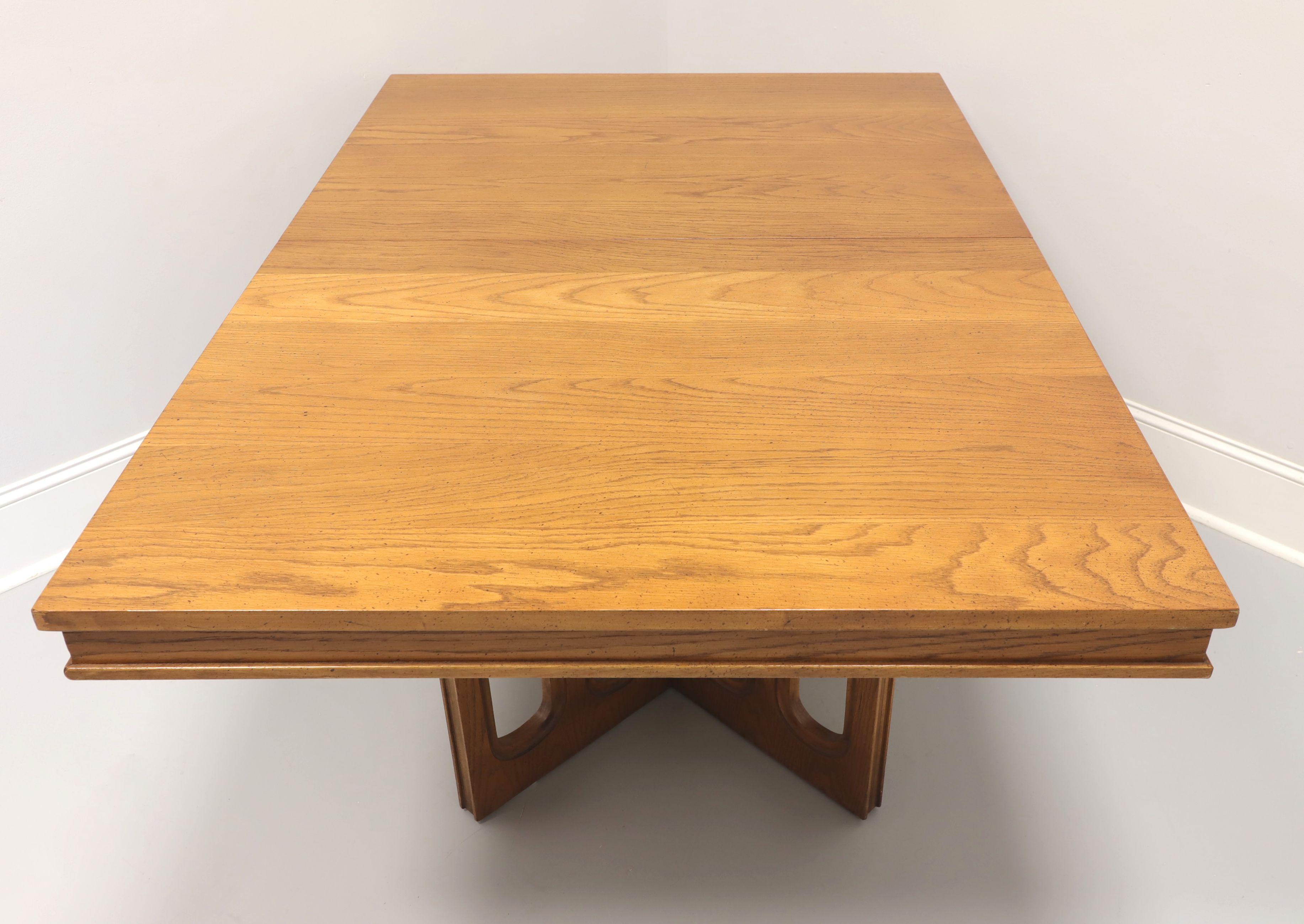 A Mid 20th Century Brutalist style rectangular dining table by Broyhill Premier. Oak with a smooth plank style top, bevel lip to apron & leaf, and dual 