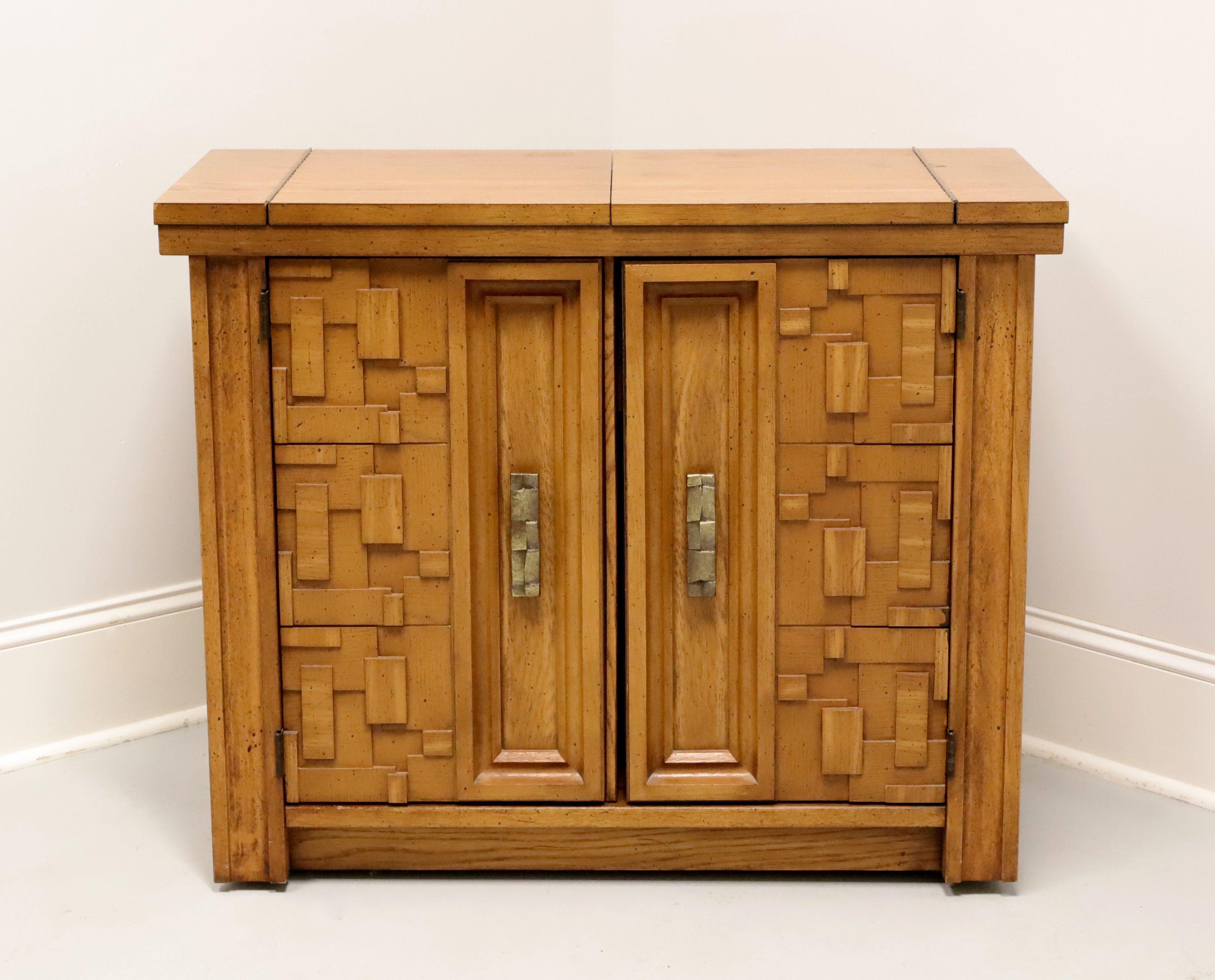 A mid 20th century Brutalist style flip top server by Broyhill Premier. Oak with slightly distressed finish, oak veneers, composite surface under the flip out top, geometric design brass hardware, raised intricately laid, highly textured, geometric