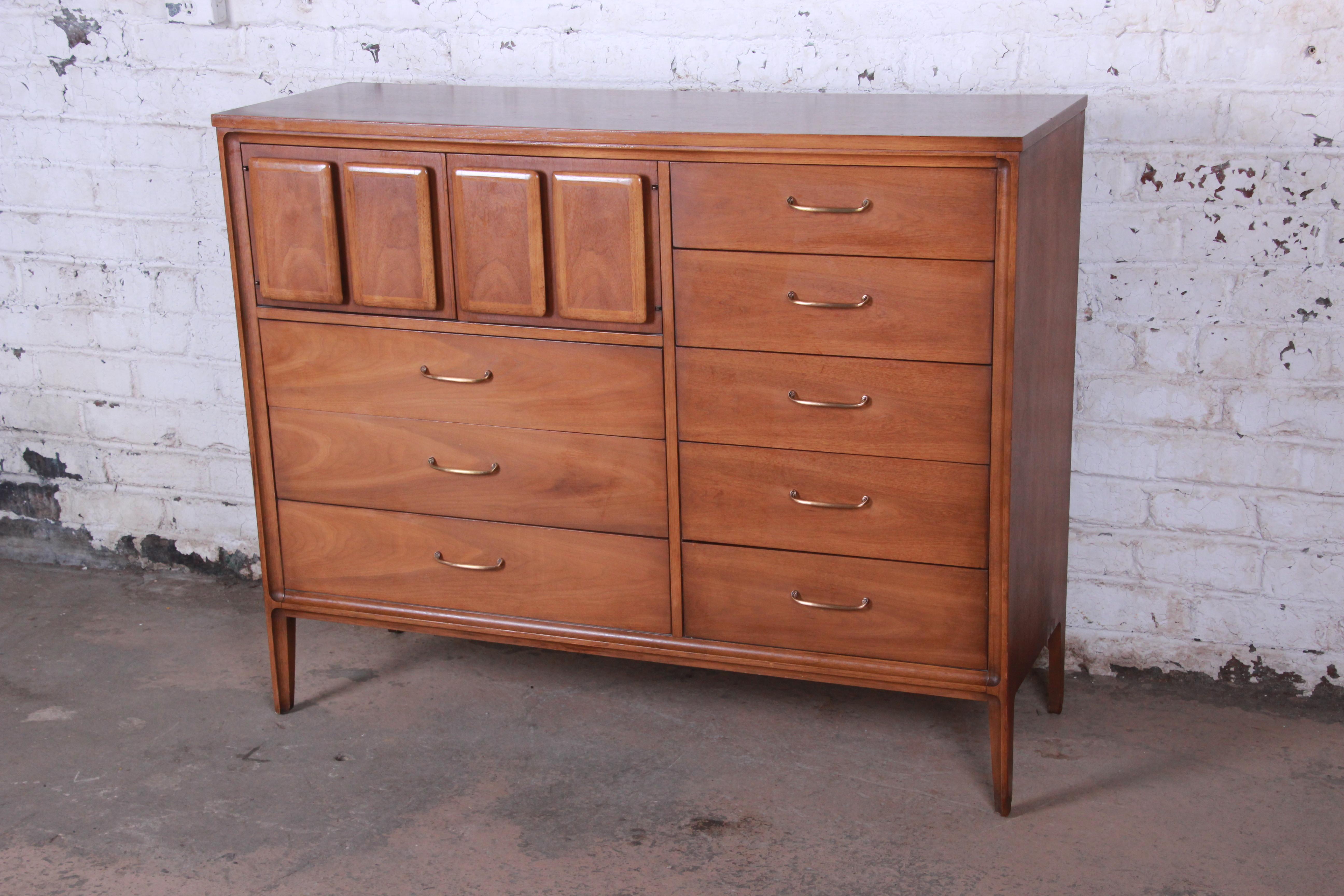 A stunning Mid-Century Modern walnut magna gentleman's chest from the Forward '70 line by Broyhill Premier. The dresser features gorgeous walnut wood grain and sleek midcentury design. It offers ample storage, with eight dovetailed drawers and three