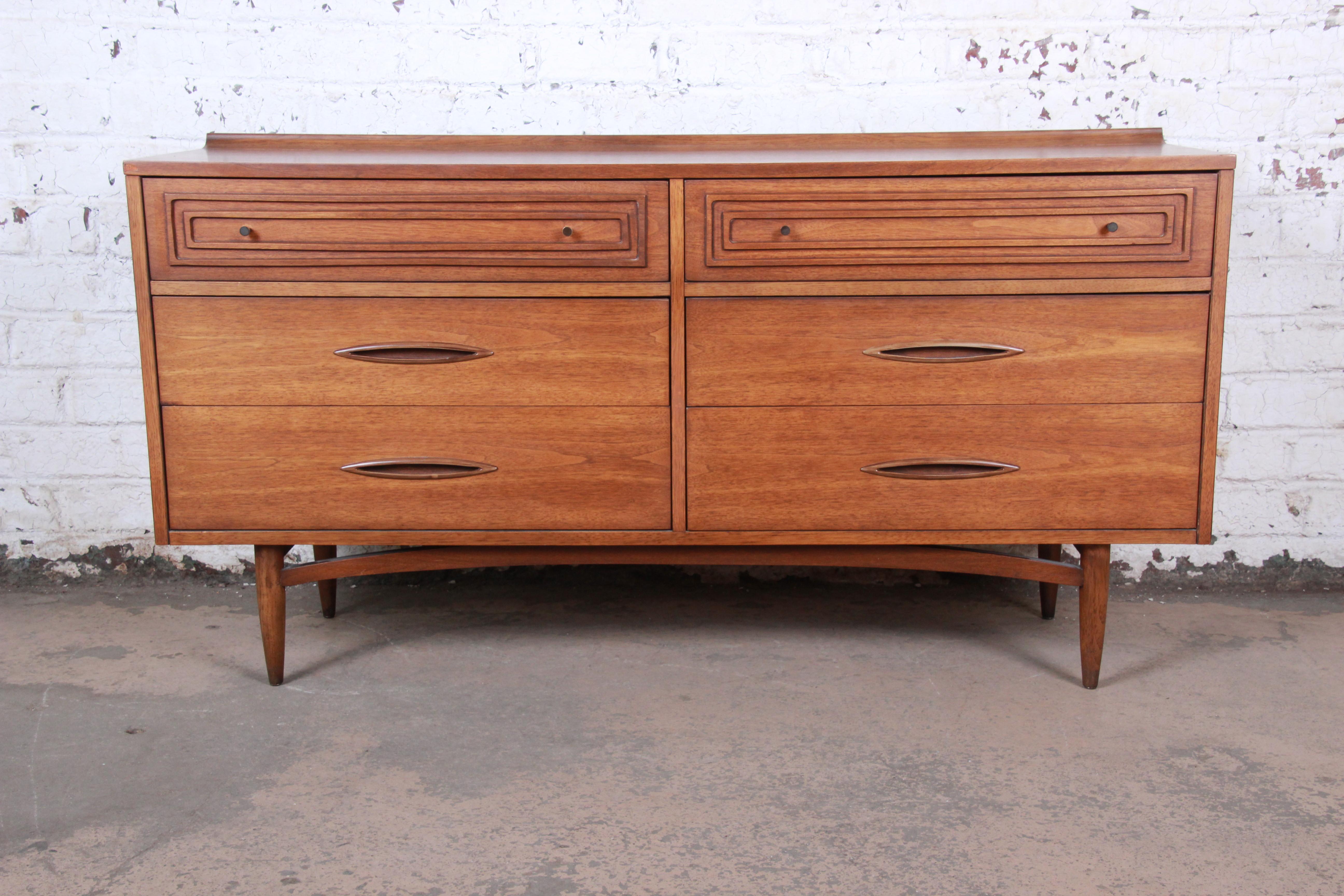 A sleek and stylish Mid-Century Modern walnut double dresser or credenza

From the Sculptra line by Broyhill Premier

USA, 1960s

Sculpted walnut and brass hardware

Measures: 60