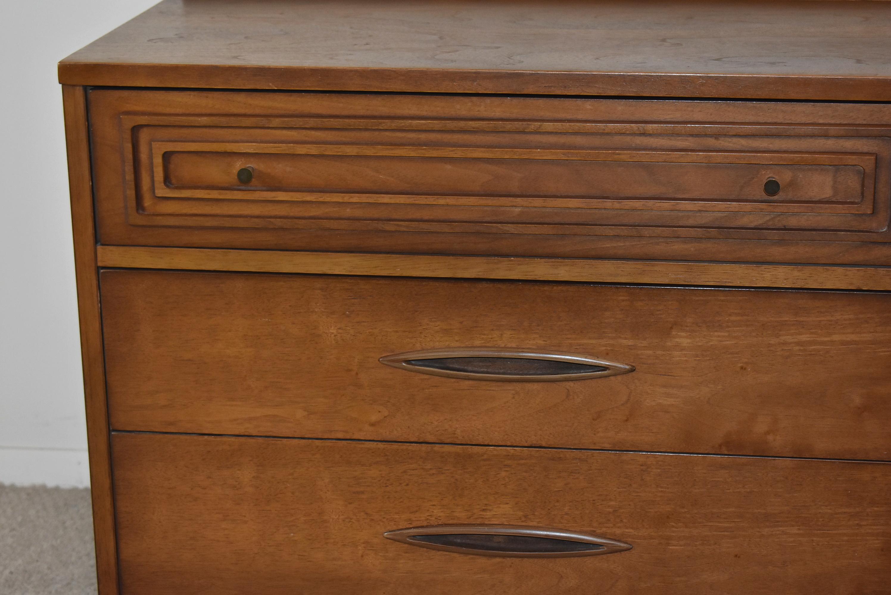 This beautiful Broyhill Sculptra dresser is made of walnut with the signature sculpture pattern on the drawers with inset elliptical handles. This piece has tapered legs with a bowed spanner. This piece has good construction with dovetail joints.