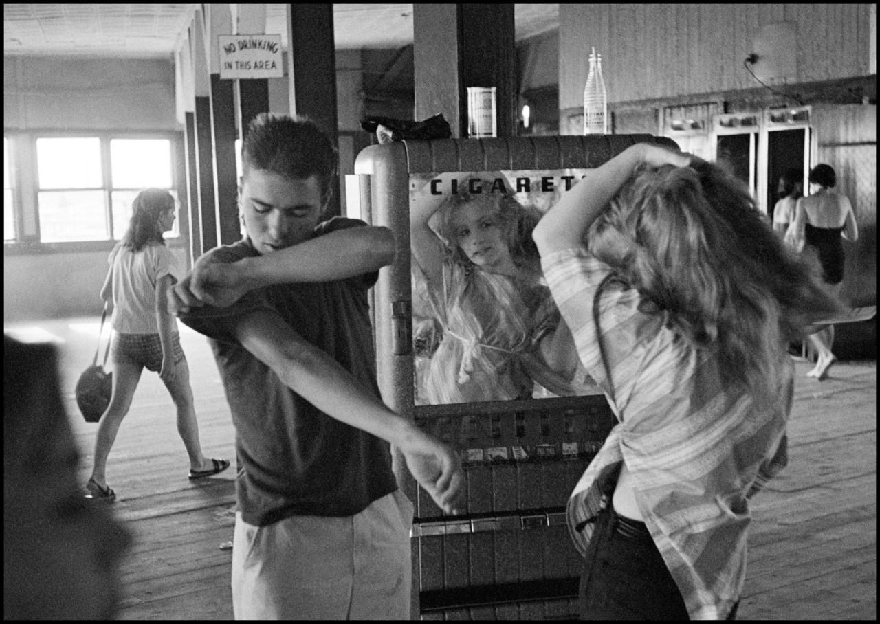 Bruce Davidson Black and White Photograph - Brooklyn Gang Kathy fixing her hair in a cigarette machine mirror, Coney Island