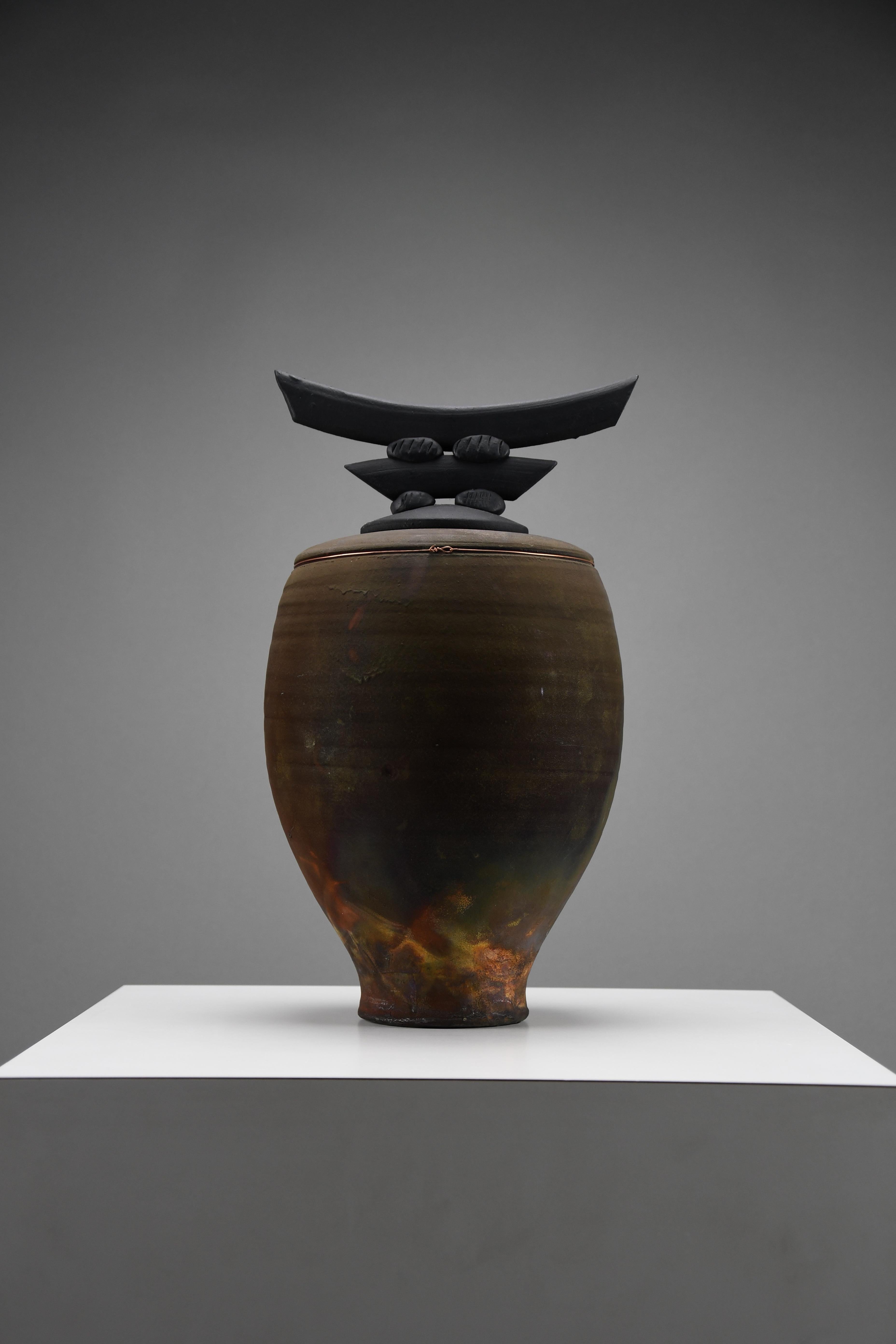 Cet exquis récipient en céramique, créé par Bruce Johnson en 1999, est un exemple frappant de maîtrise artisanale et de vision artistique. Mesurant H. 35,5 cm x D. 20 cm (environ H. 14 in x D. 7.9 in), il attire l'attention par ses proportions