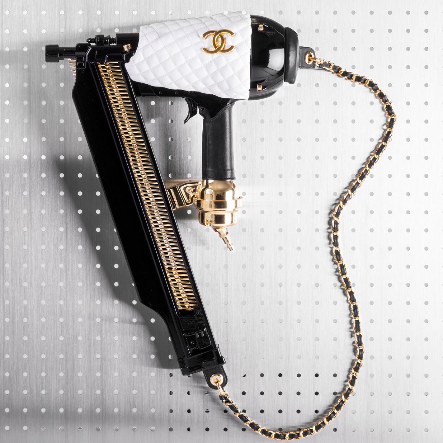 Sculpture montée d'un pistolet à ongles en cuir fabriqué à la main, décoré des embellissements classiques de Chanel. 

Le luxe n'est pas seulement un mot pour décrire l'opulence, car l'opulence sans substance n'a pas de sens. Le luxe n'est pas non