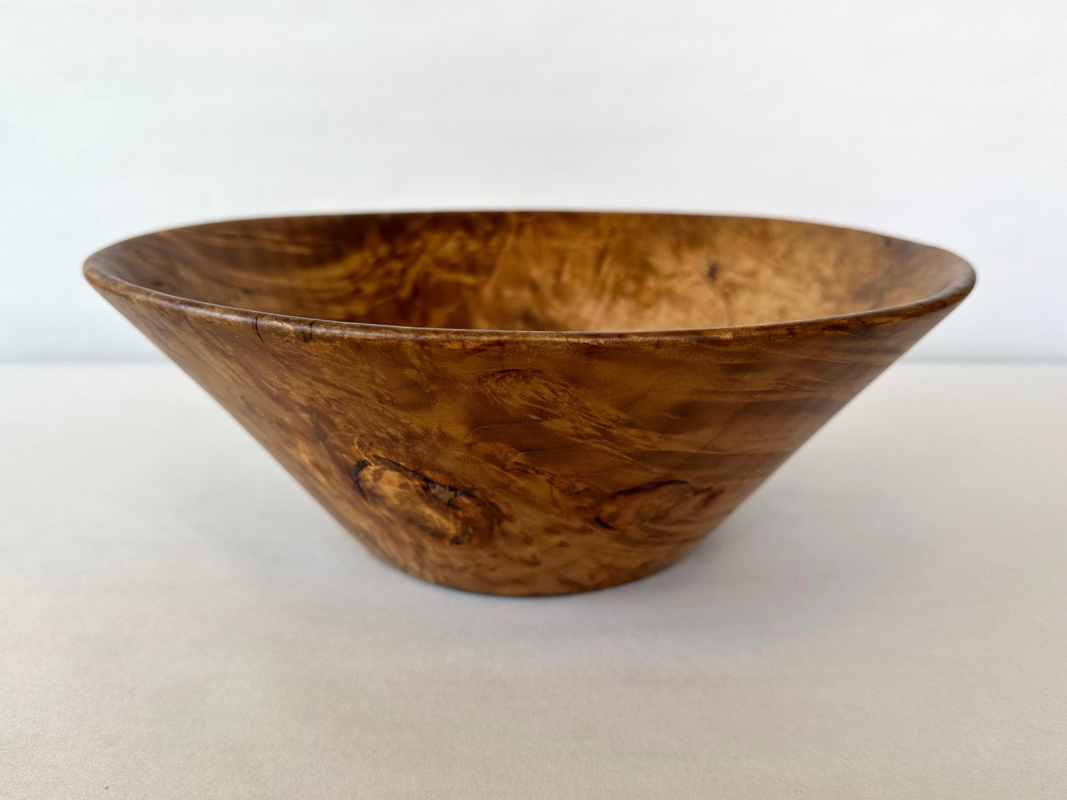 A beautiful 1979 bay laurel burl turned wood bowl by notable Marin County, California wood sculptor Bruce Mitchell.

An early work by Mitchell featuring fantastic flame-like figuring throughout. Of particular interest are a pair of slightly raised