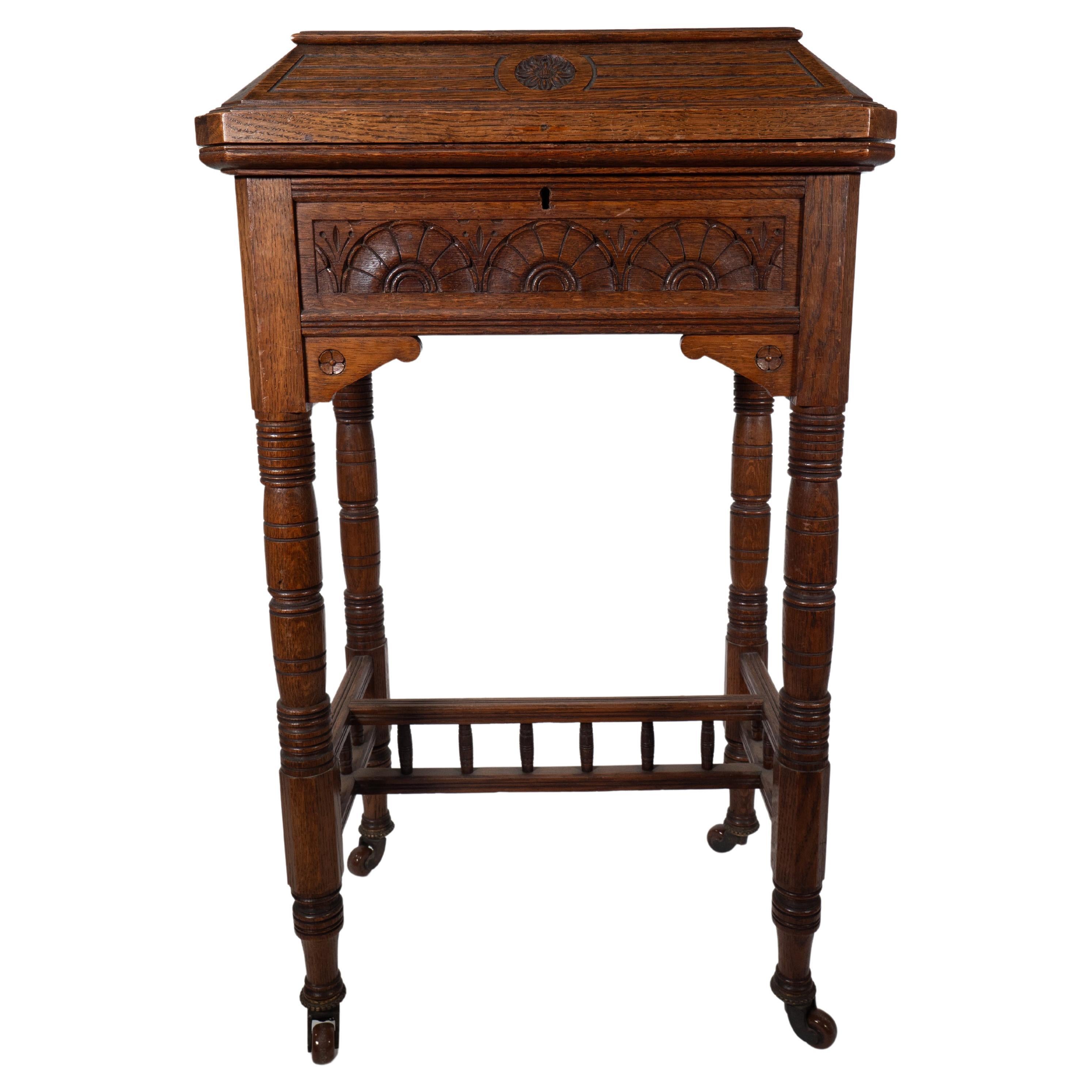 Bruce Talbert attributed. An Aesthetic Movement/Gothic Revival oak needlework table and box with carved lunettes, florets and incised turned details to the legs united with turnings to the stretchers.

