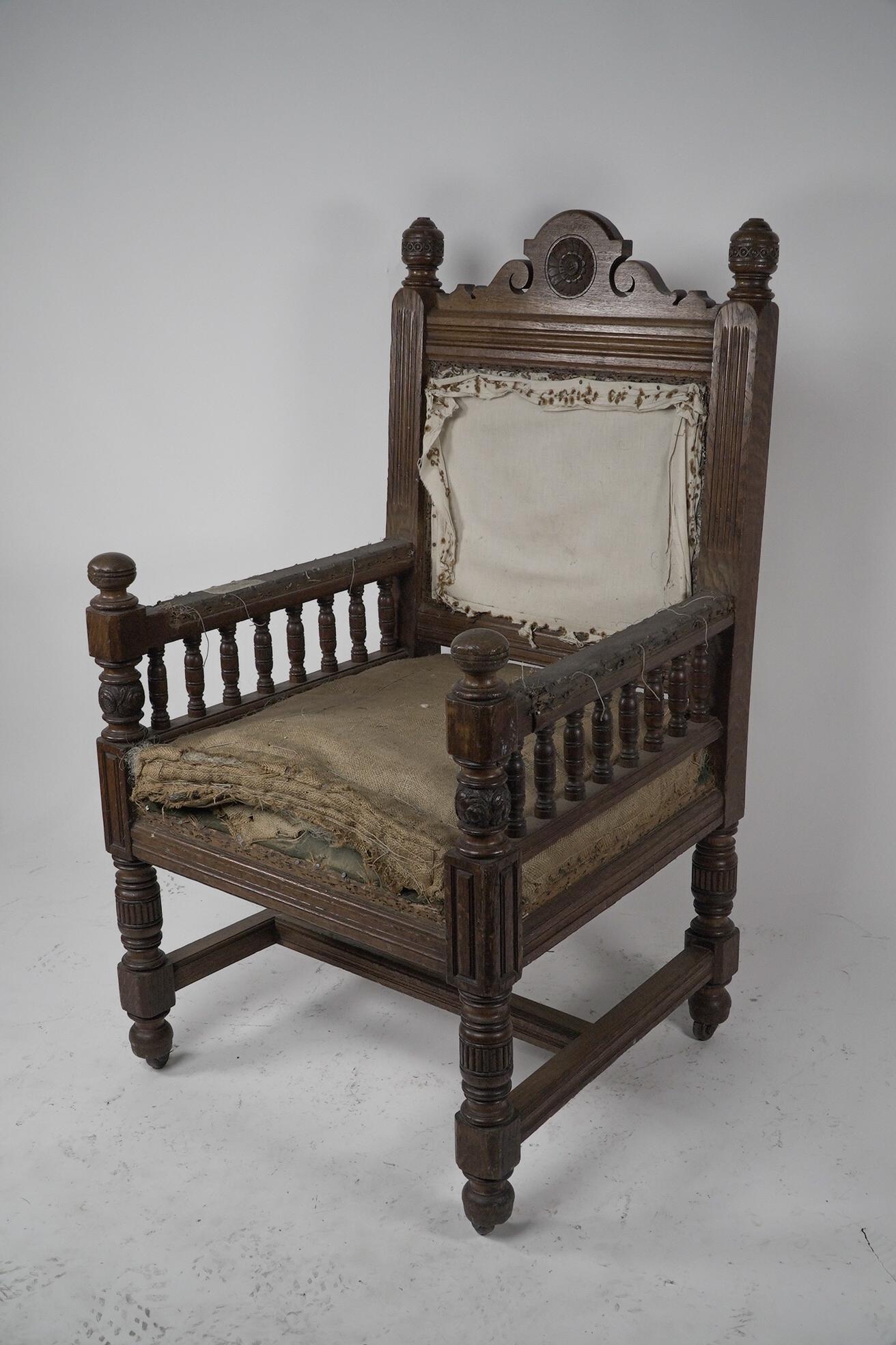 Bruce Talbert attributed, probably made by Gillows. A Gothic Revival oak armchair with a shaped head rail centered with a carved floret, flanked by carved floral finials. Beneath the arms are turned galleries and carved finials to the front. On