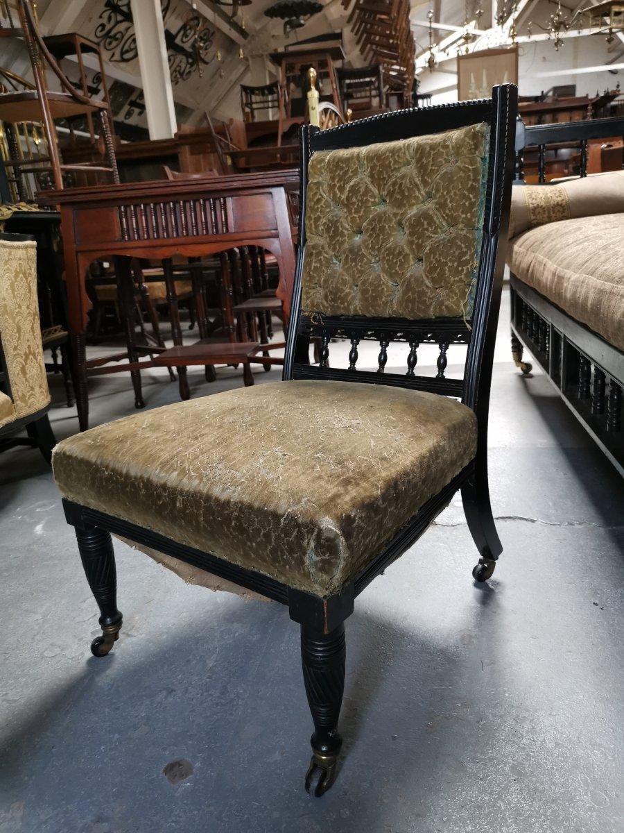 Bruce Talbert (1838-1881) for Gillow and Co., an Aesthetic Movement ebonized nursing chair, with a lobed top rail, a button upholstered crushed velvet in gold with spindles below, on ring and twist turned legs with original brass casters.