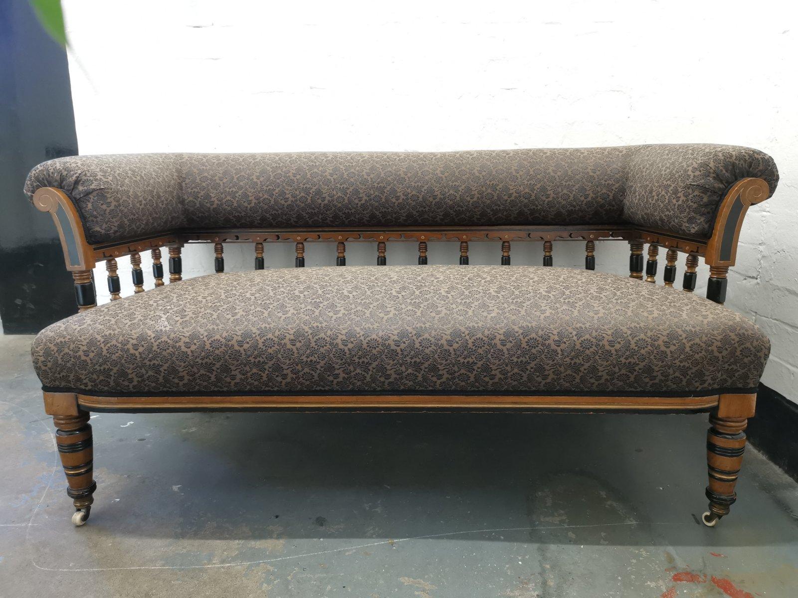 Bruce Talbert, for Gillows of Lancaster and London. 
A very good quality English Aesthetic Movement ebonized and parcel-gilt upholstered settee with a rollover back and arms with incised scroll and ebonized and parcel-gilt decoration to the front,