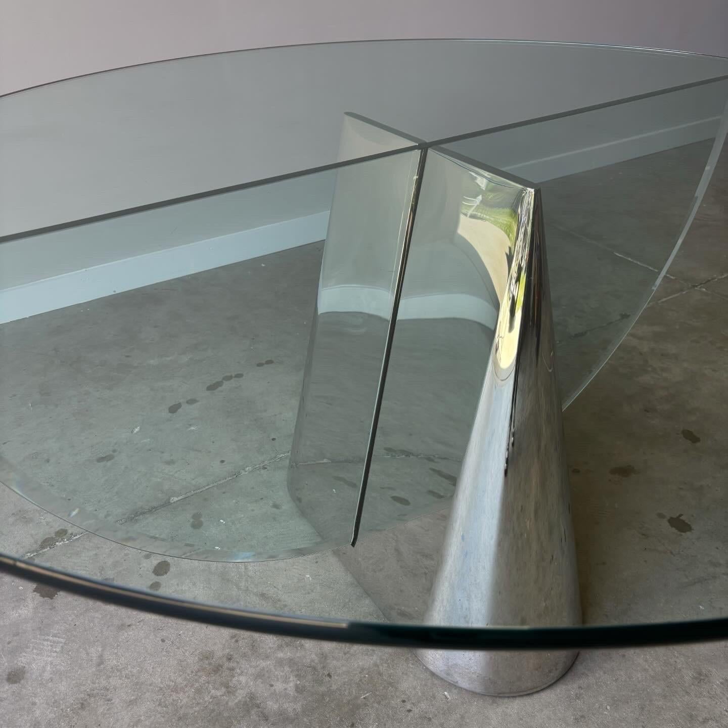 Ésta es la Mesa Pinnacle, diseñada por J. Wade Beam para Brueton. Este diseño clásico moderno presenta un pedestal central cónico de acero inoxidable pulido intersecado por un cristal de 3/4