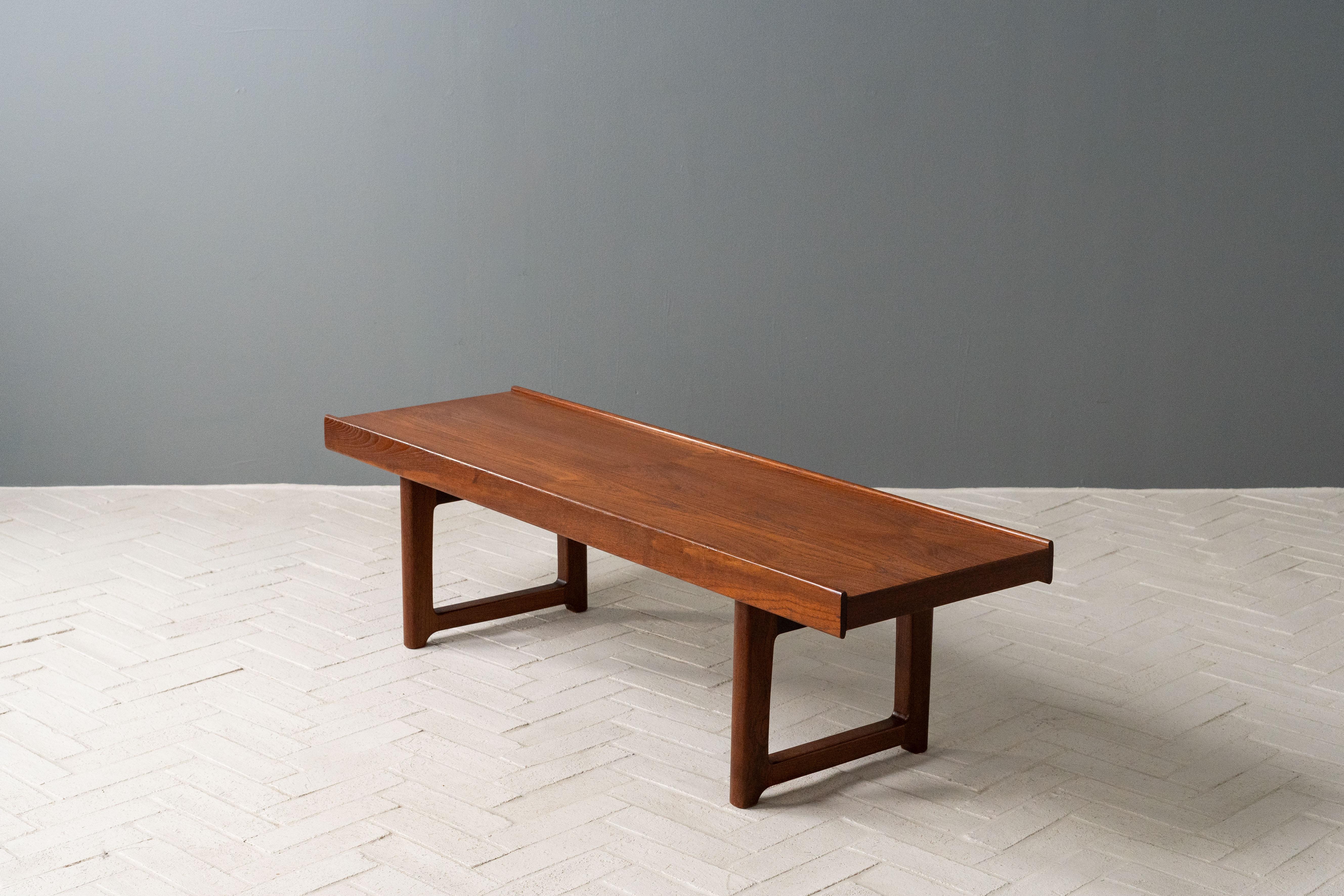 Norvège, vers les années 1960. Une belle table basse ou un banc Krobo par Torbjørn Afdal pour Bruksbo. Fabriqué en teck, ce meuble est doté de pieds robustes en forme de traîneau, soutenus par des supports en acier émaillé noir. Le rebord parallèle