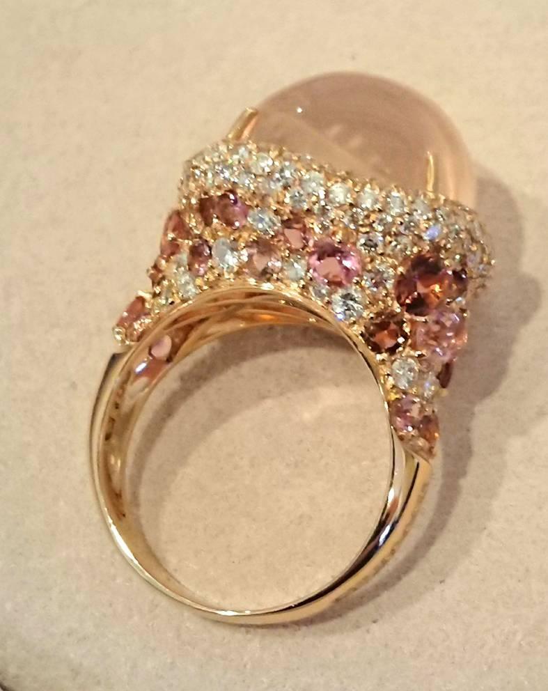 An amazing bombe ring from Brumani. Featuring a feature cabochon rose quartz sat upon a border of pave diamonds. The shoulders are covered in rare pink sapphires and diamonds. The setting is 18ct rose gold with makers mark and full British assey