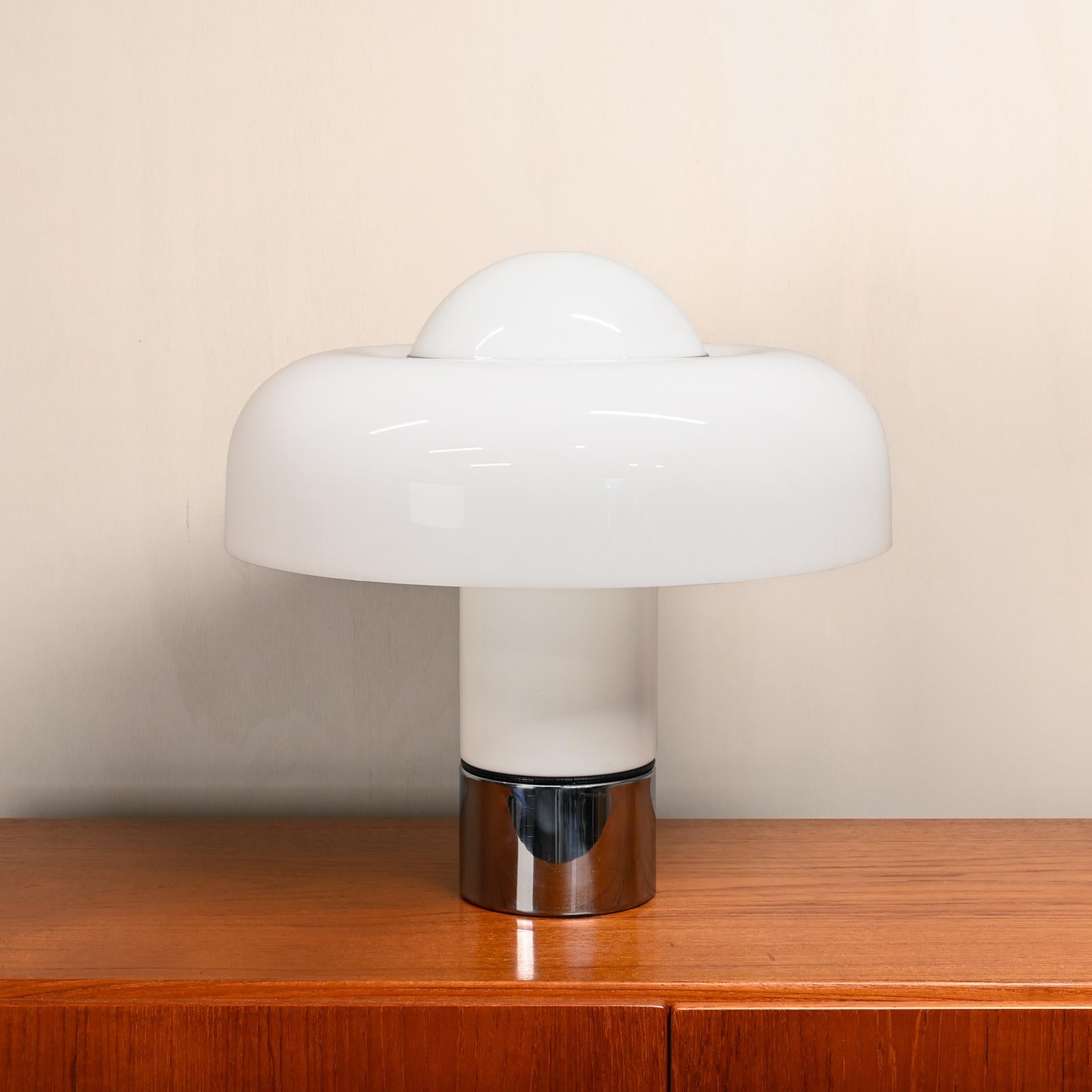 Stylish and iconic table and/or desk lamp 'Brumbury' designed by Luigi Massoni for Guzzini. The top consists of a white acrylic shade twisted with a chrome ring and is attached with 3 chrome ball nuts to the metal bottom with chrome base. The lamp