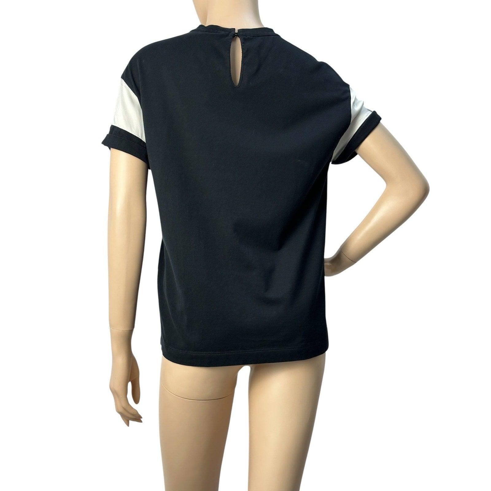 Esta camiseta negra de Brunello Cucinelli es muy elegante y fácil de combinar. La raya de satén brillante añade un toque de lujo, mientras que los detalles de la firma Monili elevan el diseño. 

La silueta drapeada y el tejido de punto fluido crean