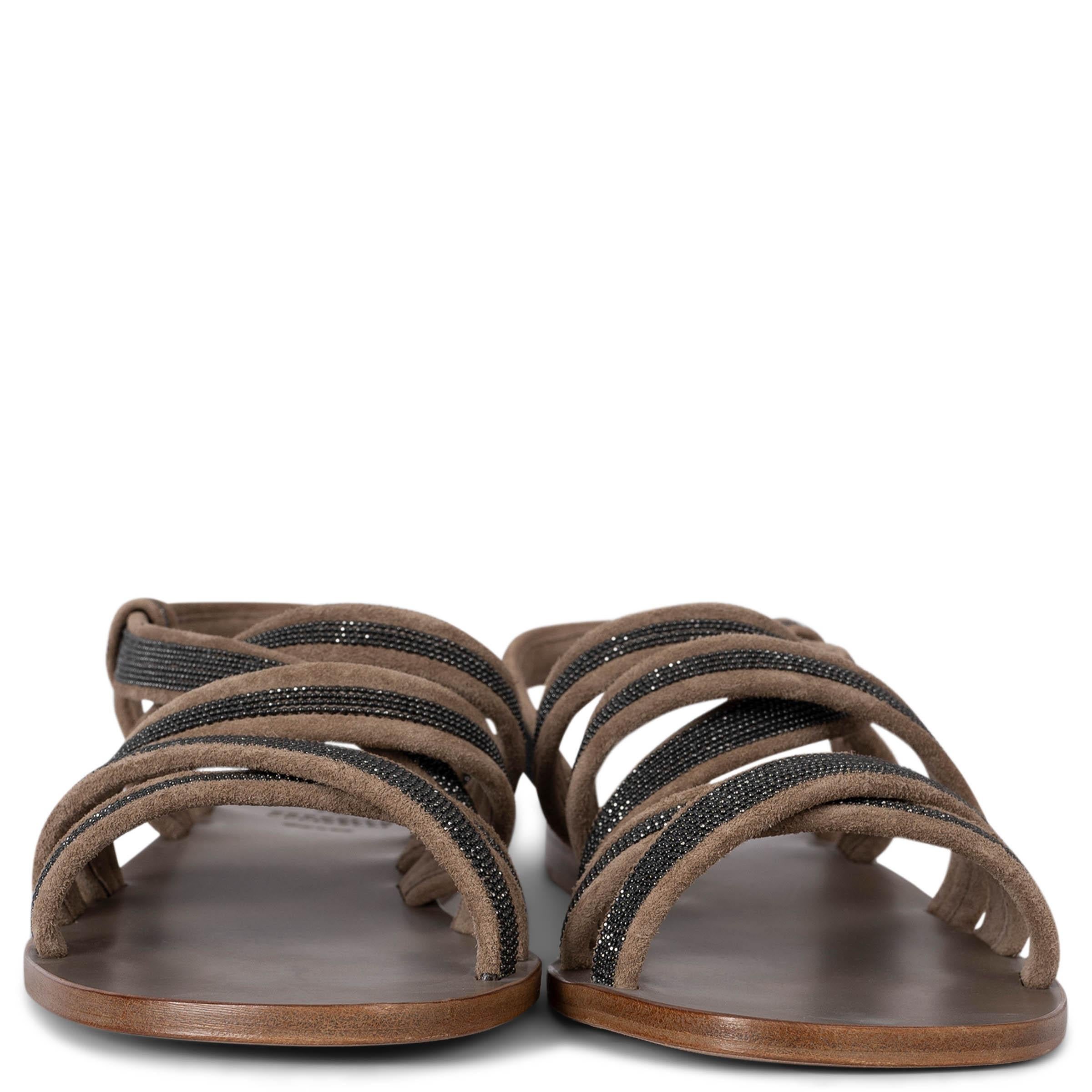 These 100% authentic Brunello Cucinelli flat sandals are crafted from pale brown suede and feature dark grey Monili bead trim on all straps, adding a touch of elegance to the design. The sandals include an ankle strap for a secure fit and leather