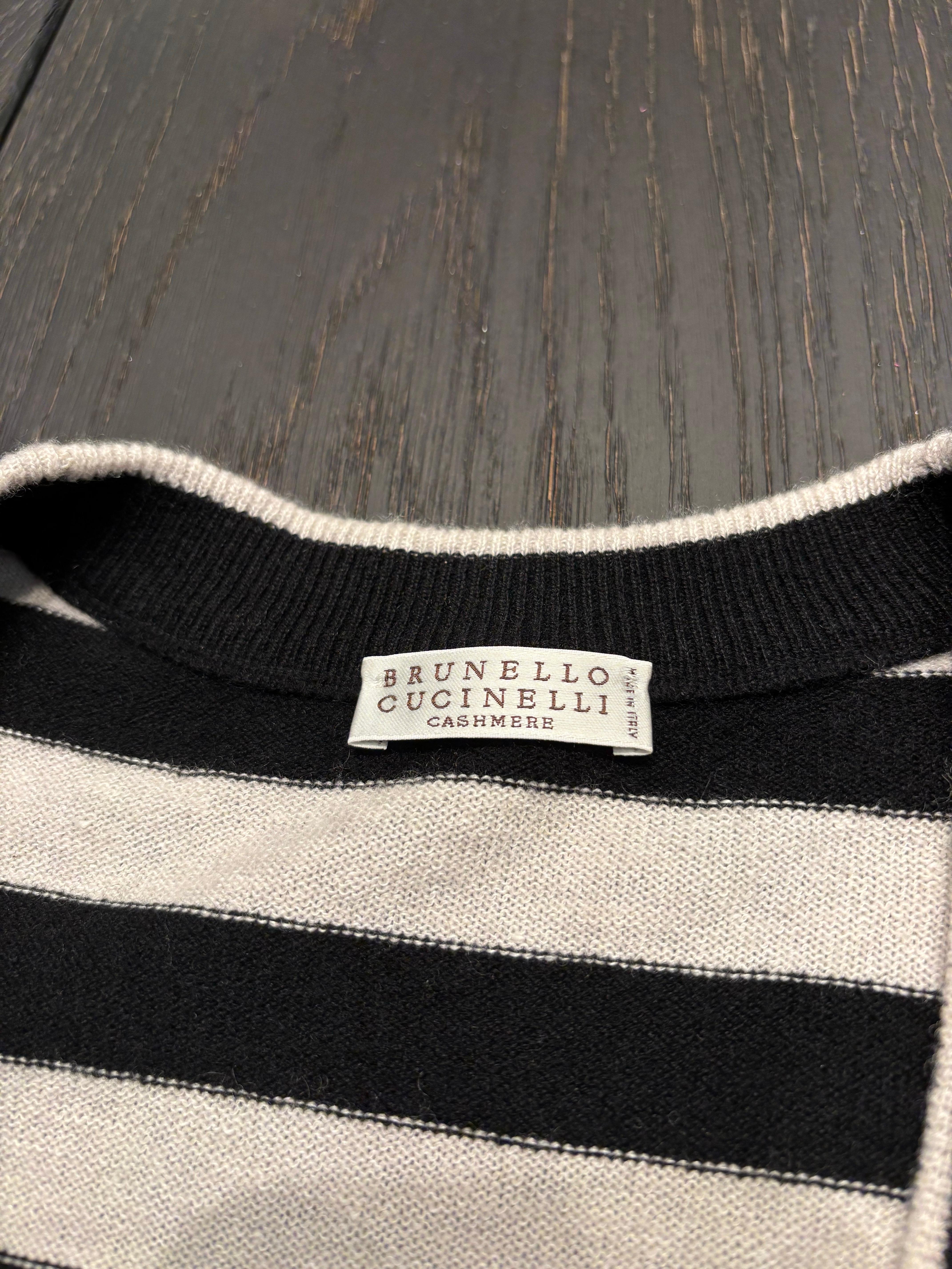 
Eine luxuriöse Kaschmirjacke von Brunello Cucinelli mit klassischen schwarz-cremefarbenen Streifen und schwarzen Pailletten, die dezent in mehrere Streifenreihen eingewebt sind. Dieses Stück spiegelt Cucinellis 