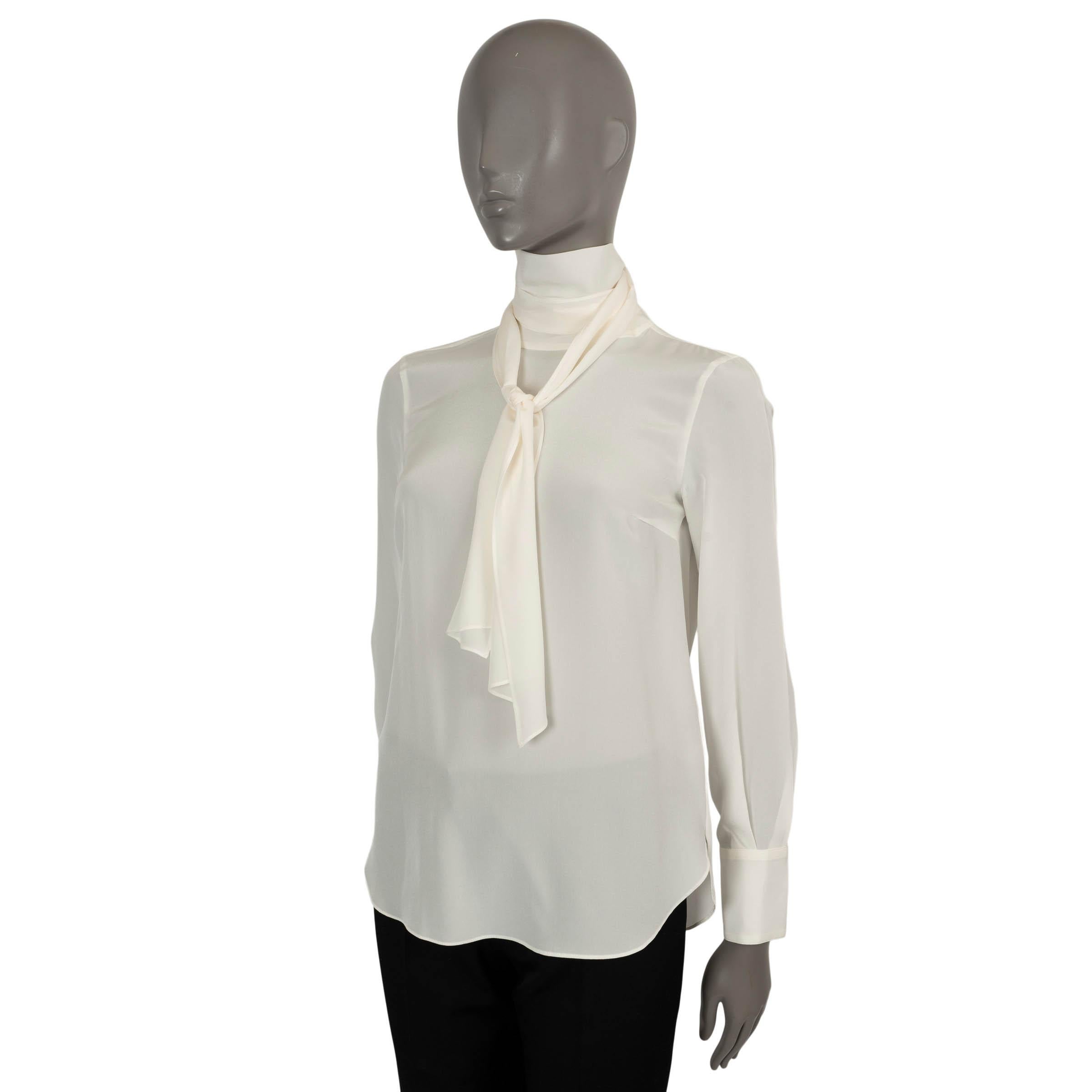 100% authentic Brunello Cucinelli semi-sheer blouse in cream silk (100%). Features a relaxed fit, mock-neck with lavalier, a curved hem and wide cuffs. Closes with a buttons in the neck. Unlined. Has been worn and shows faint armpit stains. Overall