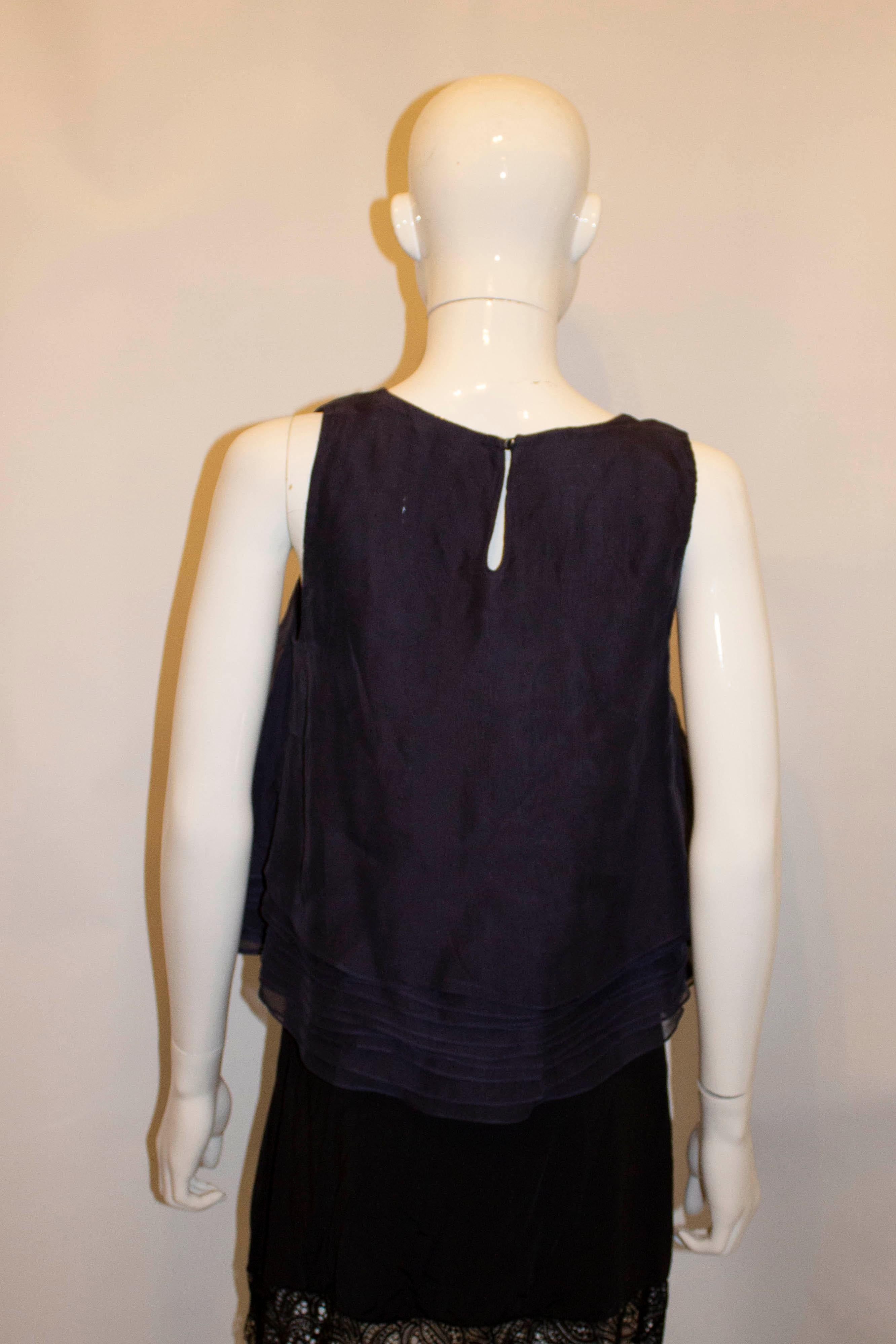 A chic and easy to wear top by Brunello Cucinelli. The top is  A line and in several layers of navy silk. It has a button opening at the back with silver trim . Made in Italy. Size M Bust up to 36'', length 21''