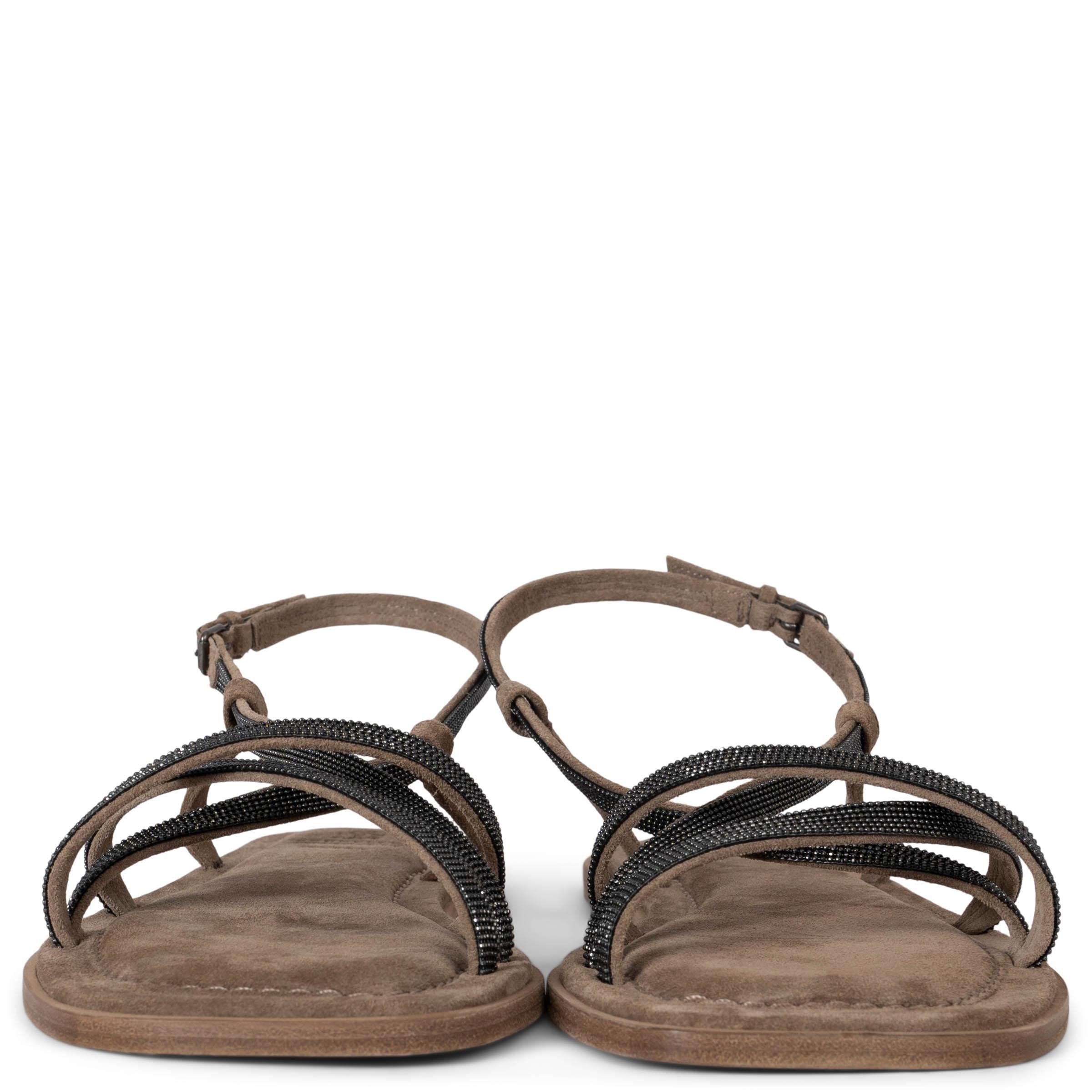 These 100% authentic Brunello Cucinelli New Ice flat sandals are crafted from taupe suede and feature elegant straps adorned with dark grey Monili beads. The design includes ankle straps with silver-tone metal buckles and leather soles with rubber