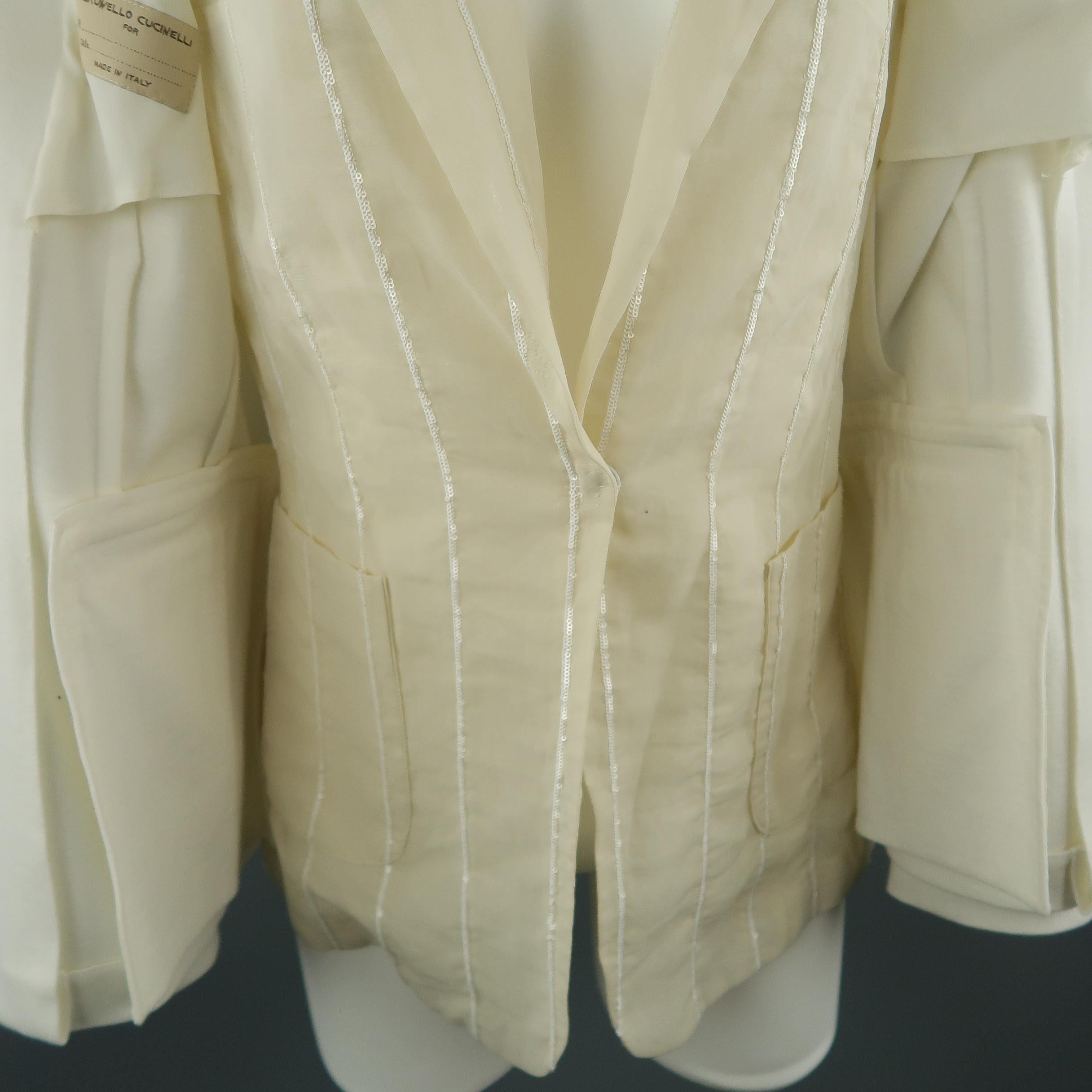 BRUNELLO CUCINELLI blazer comes in cream jersey knit with a peak lapel, single button, and inner beige chiffon lapel layer with white sequin trim. Made in Italy.
 
Excellent Pre-Owned Condition.
Marked: IT 38
 
Measurements:
 
Shoulder: 14.5