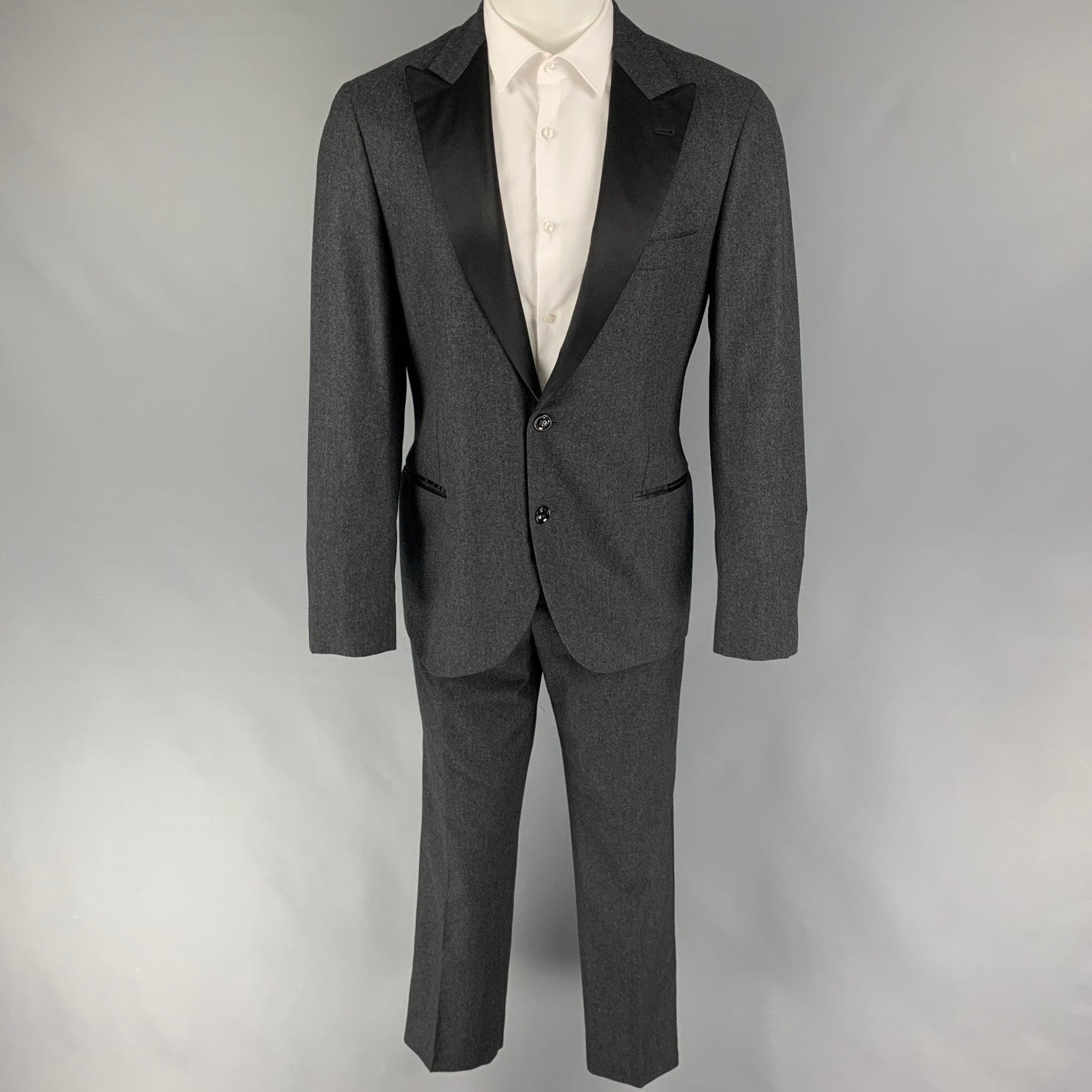 BRUNELLO CUCINELLI
Le costume de smoking est en laine mélangée grise et noire avec une doublure complète et comprend un manteau de sport à un seul boutonnage avec un revers en pointe et un pantalon assorti à devant plat. Comprend un sac à vêtements.
