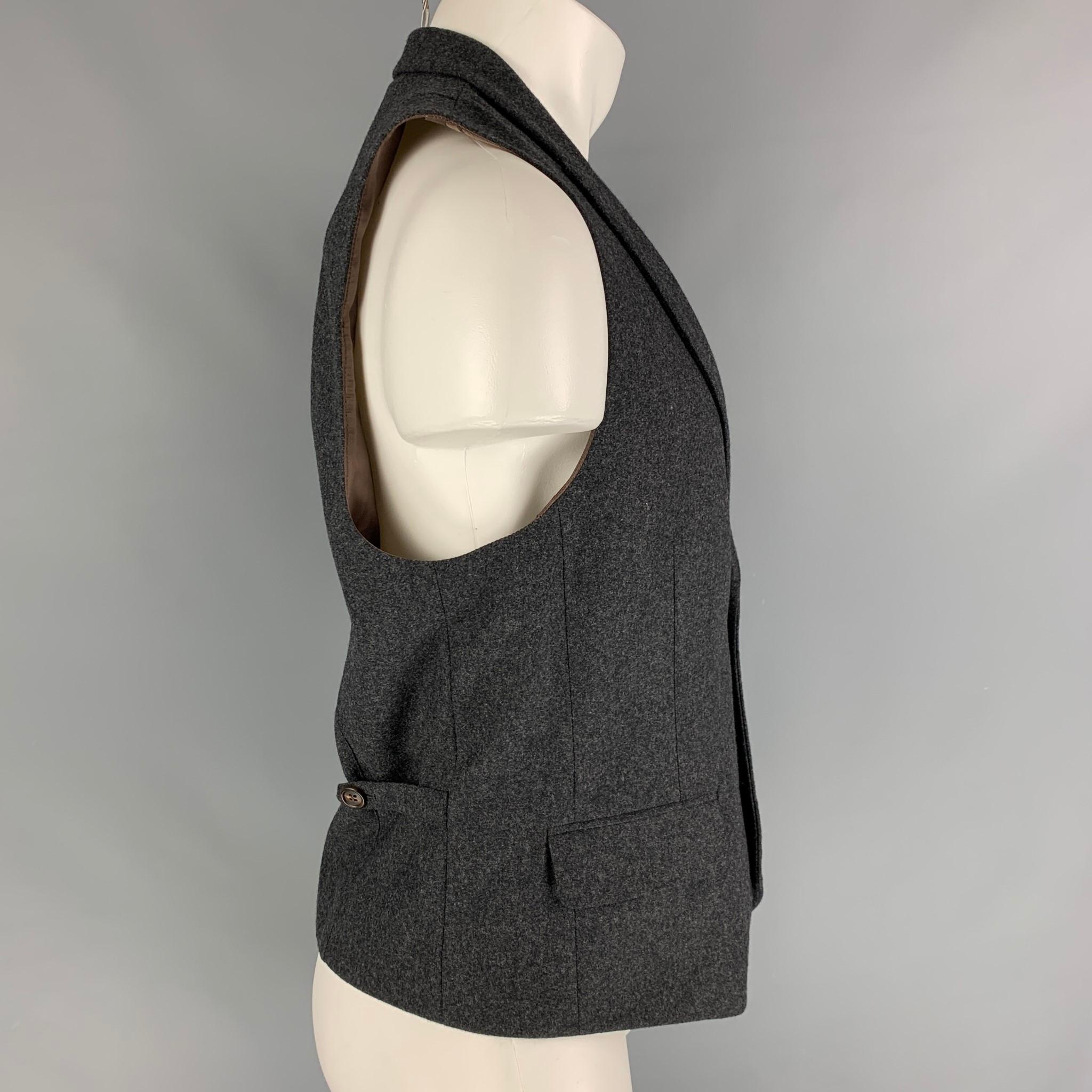 BRUNELLO CUCINELLI vest comes in a charcoal heather wool featuring a notch lapel, side tabs, flap pockets, and a buttoned closure. Made in Italy. 

Very Good Pre-Owned Condition.
Marked: 50

Measurements:

Shoulder: 14 in.
Chest: 38 in.
Length: 23