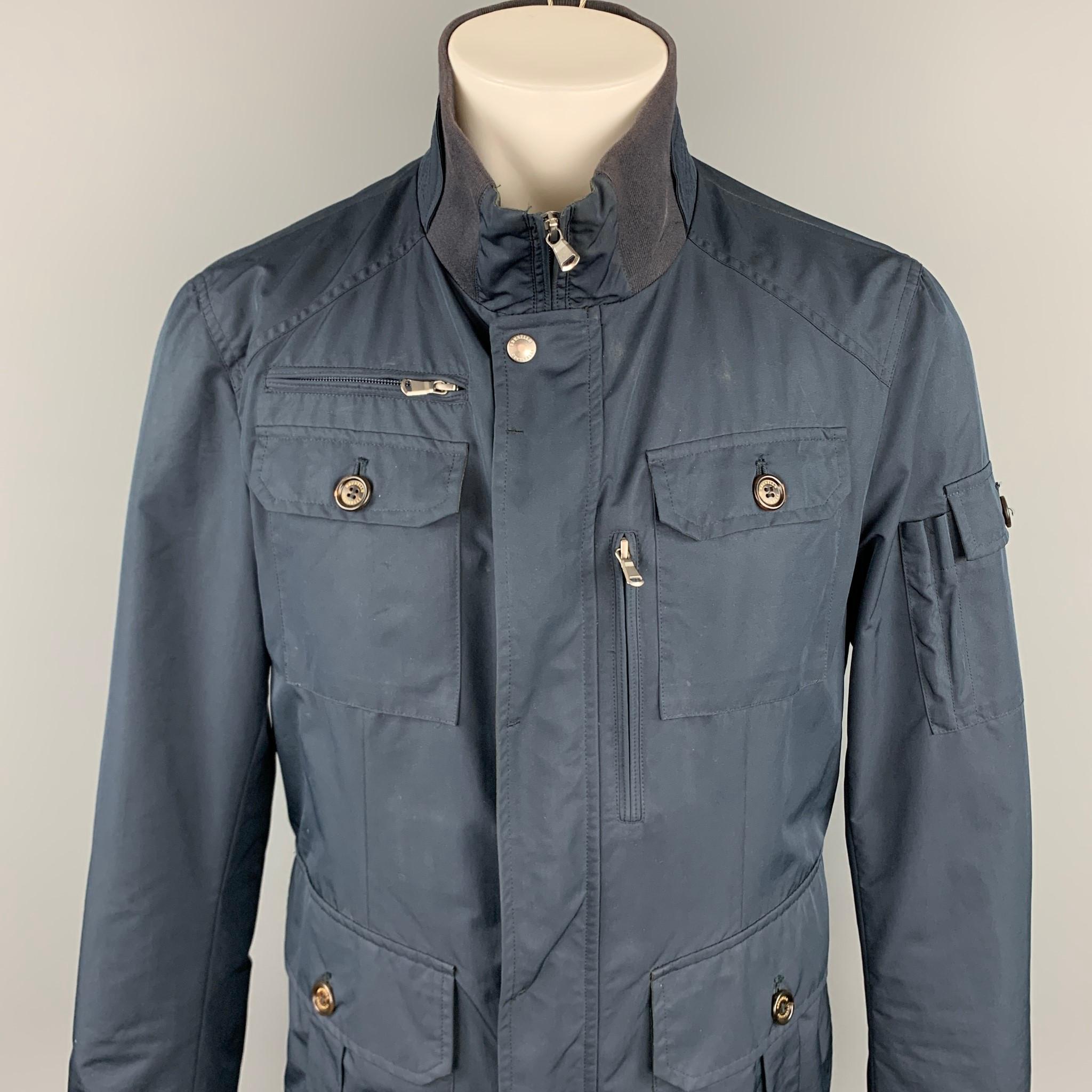 BRUNELLO CUCINELLI jacket comes in a navy nylon featuring a ribbed high collar, patch pockets, sleeve pocket, and a buttoned & zip up closure. Made in Italy.

Excellent Pre-Owned Condition.
Marked: M
Original Retail Price: