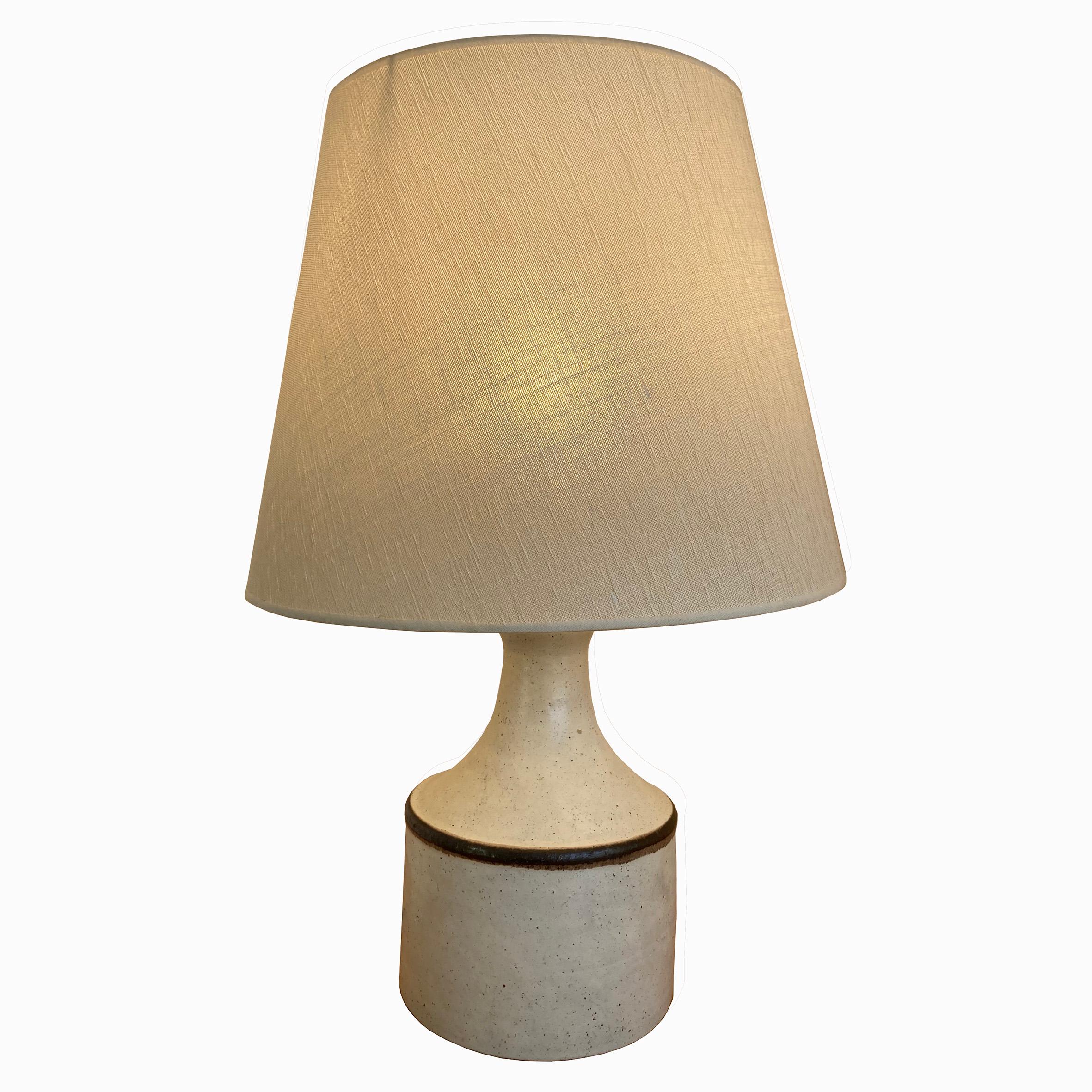 Bruno Gambone (1936-2021)

Table lamp

A light grey ceramic table lamp, with a cylindrical body decorated with a black line at the rim, surmounted with a trumpet shape stem.
With a light grey fabric shade.
Signed underneath « Gambone,
