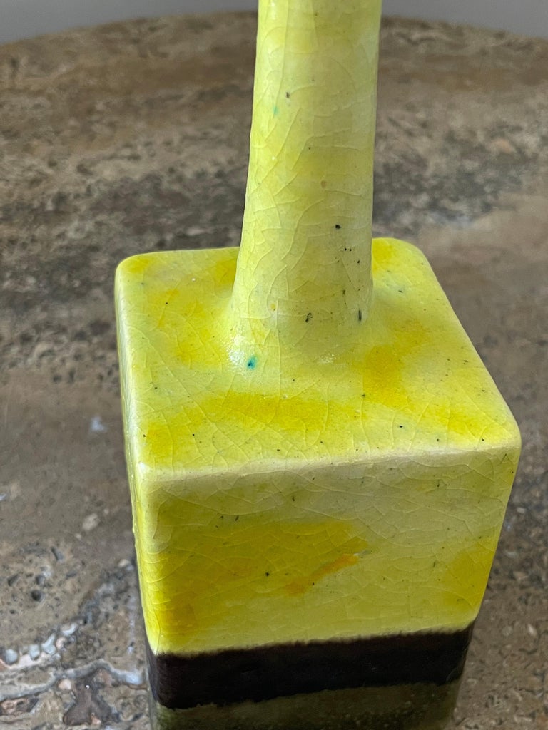 An unusual vase designed by Bruno Gambone. Features a vibrant yellow color which is different from his typical use of color palette. Interesting shape starting with a square base and tapering to a round neck. Very good condition.