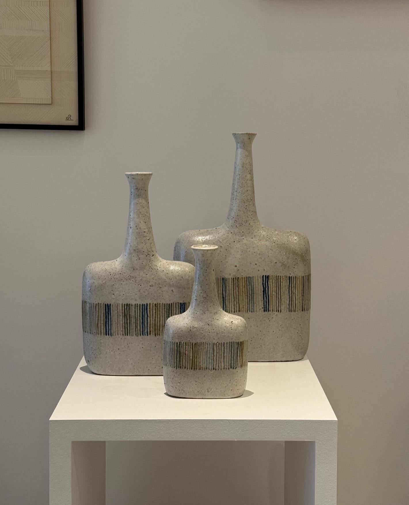 Ensemble de 3 vases bouteilles en céramique signés par Bruno Gambone 1970
Faïence émaillée beige avec des bandes colorées au centre
Mesures : H 40 cm / H 33 cm / H 23 cm et L : 23/19/13 cm
Signé Gambone Italie 

