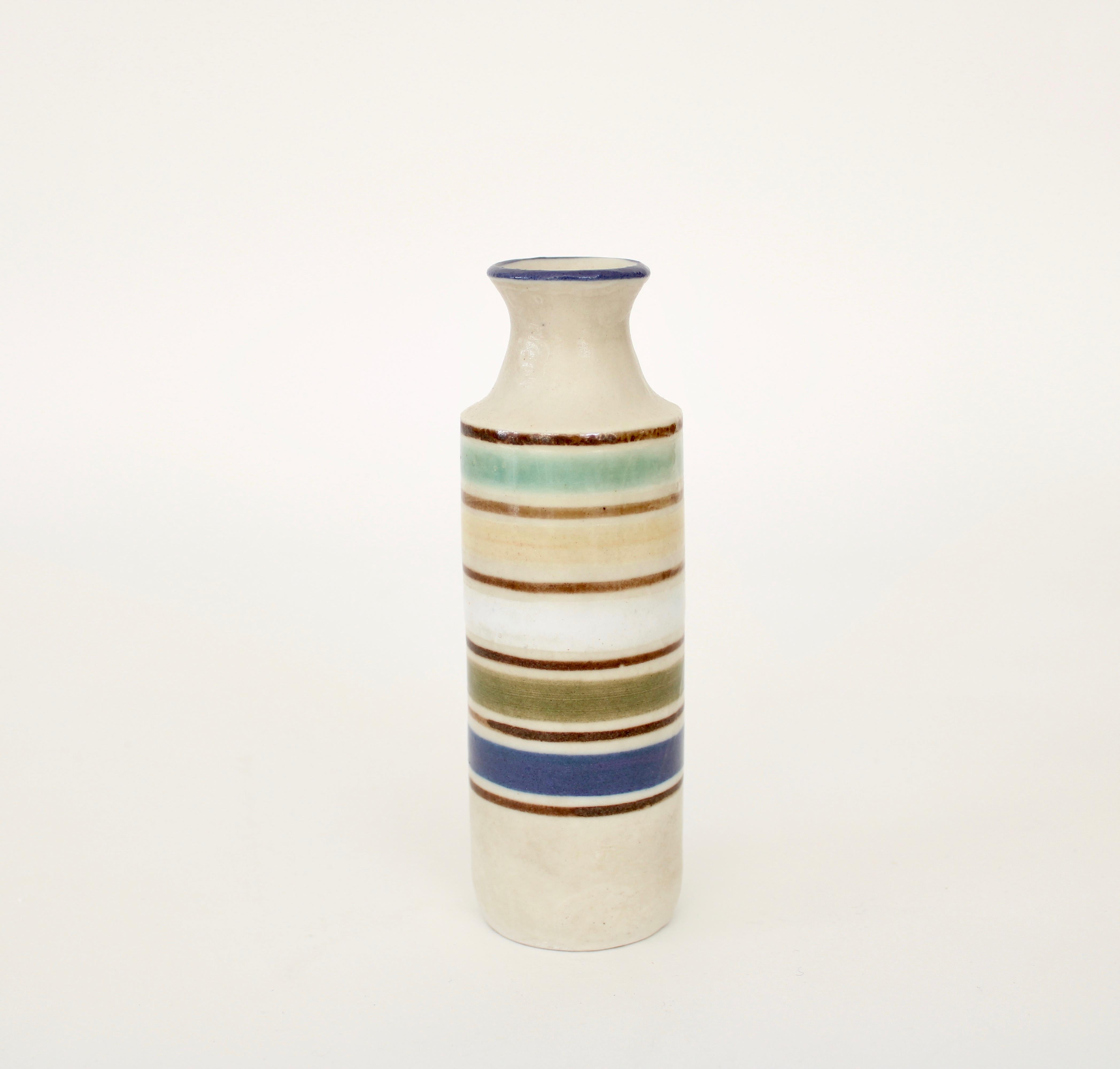 Bruno Gambone decorative ceramic mini bottle-shaped vessel with cream glazed surface and multi colors circling the bottle. (circa 1970s). 
The various colors make this bottle unique among the small collection offered and is exceptionally desirable