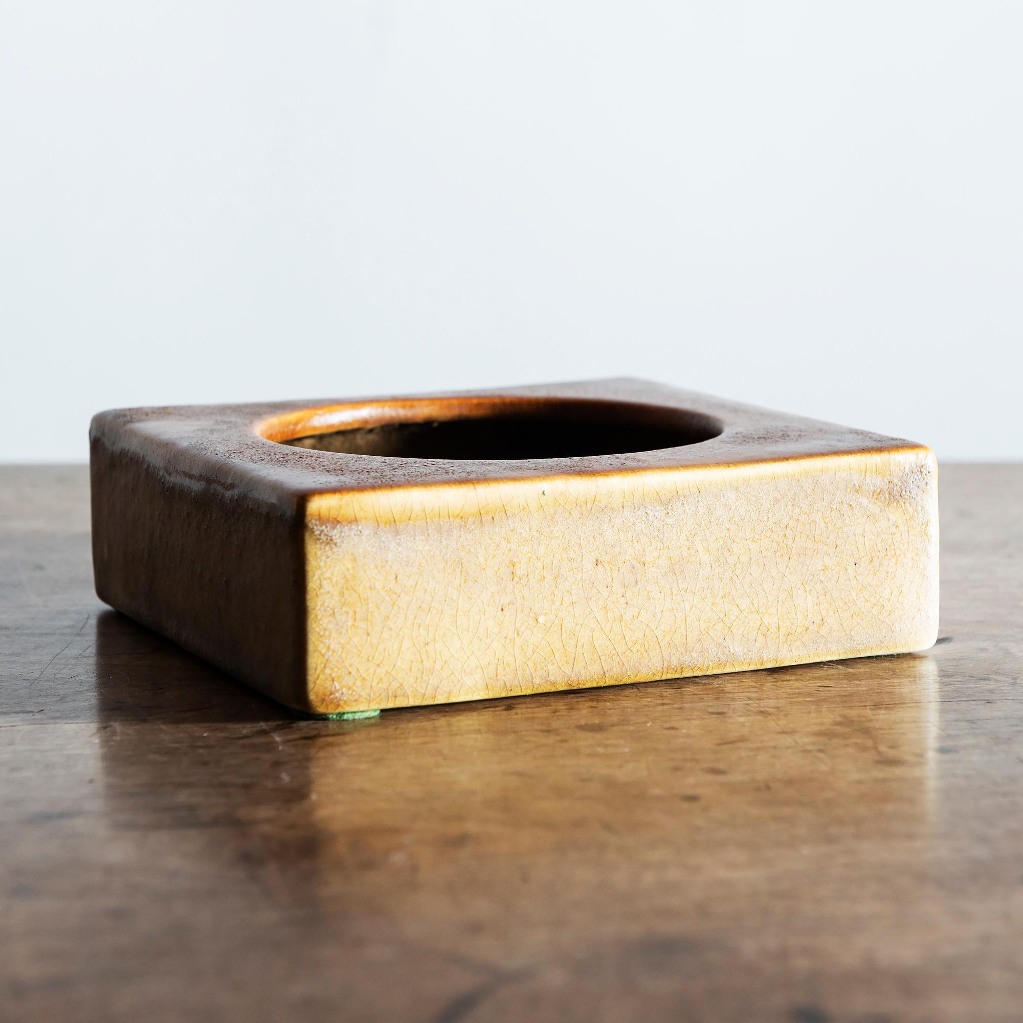 Square ceramic bowl glazed on the exterior in honey and burnt caramel. Concentric circles in black, brown and orange on the interior. Signed on underside, Italy, 1960s.