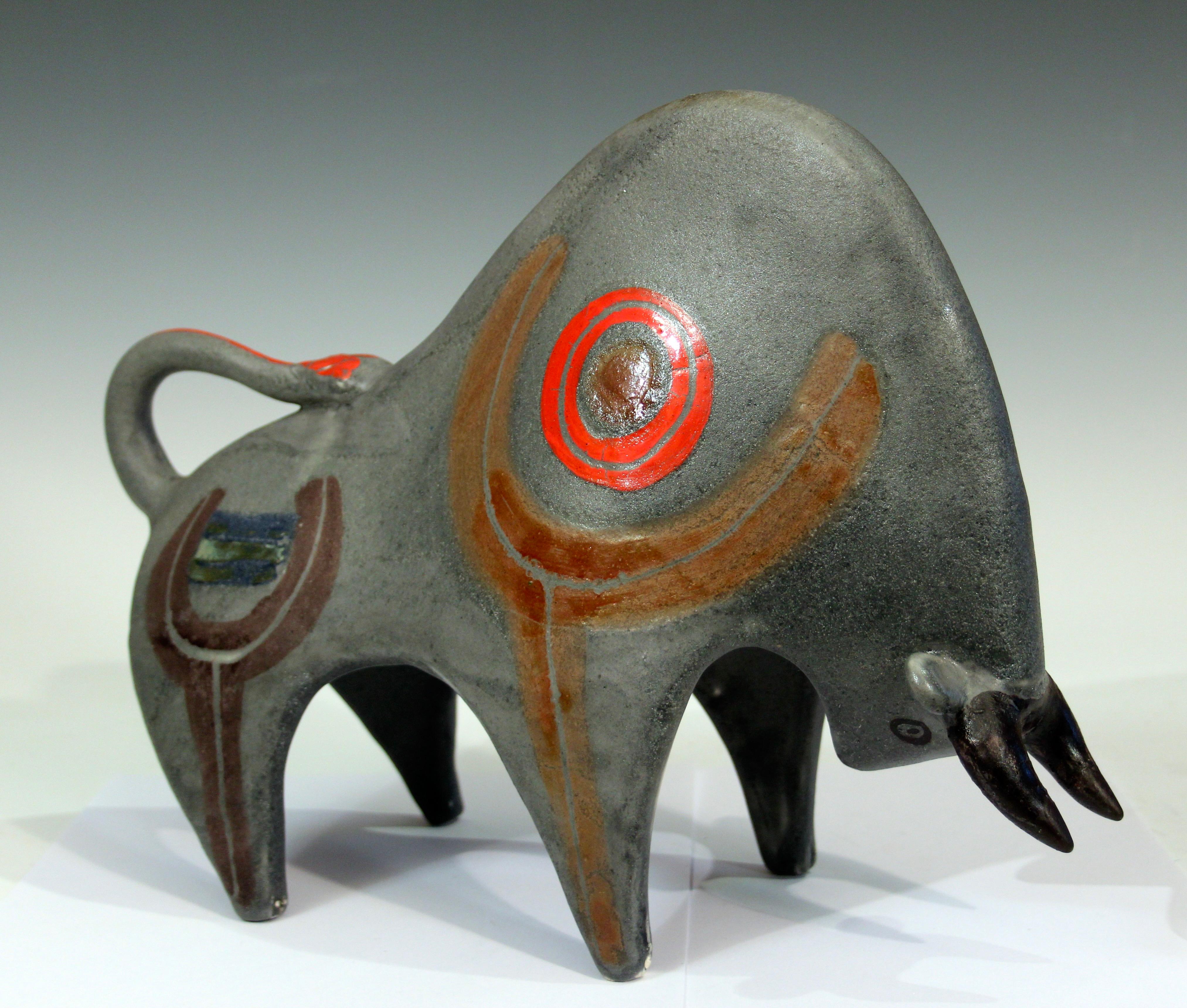 Large vintage Bruno Gambone pottery bull figure in partially abstracted form with repetitive sweeping curves and enameled totemic symbols on a variegated gray ground, circa 1970's. 13 1/2