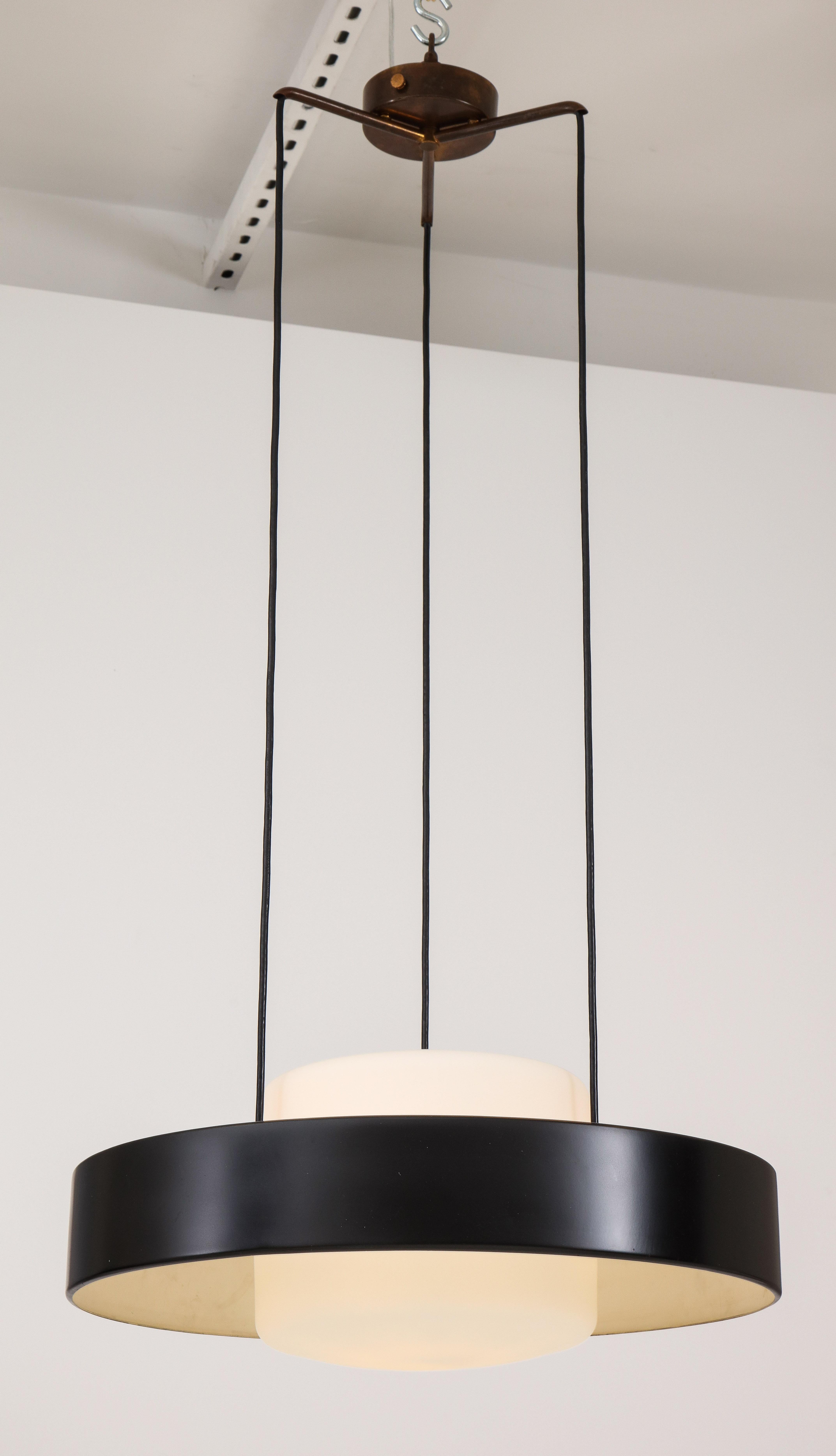 Stilnovo iconic chandelier model 1158 composed of black enameled metal ring and opaque glass shades suspended from original brass canopy and structure, Italy, 1960s. This adjustable ceiling light emits light beautifully with its opaque glass shades