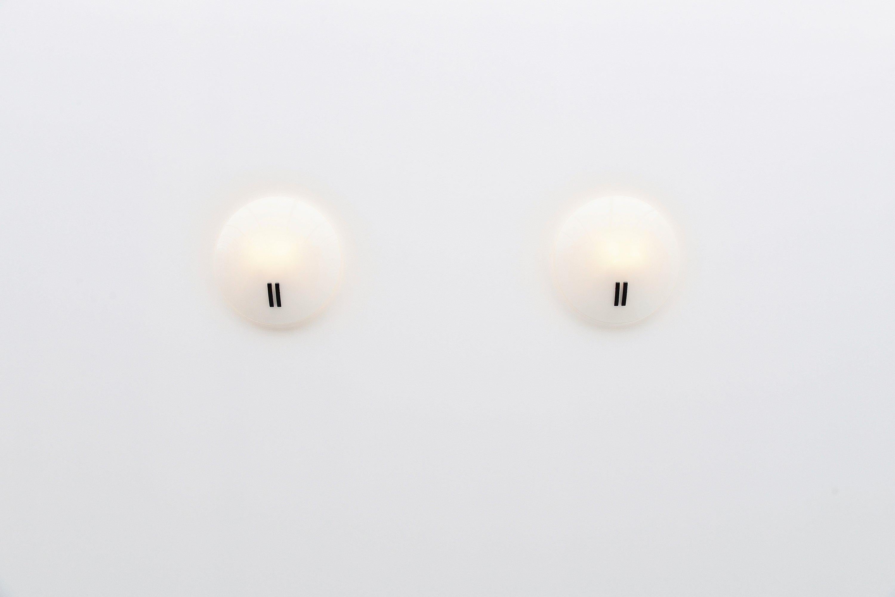 Large pair of wall lamps designed by Bruno Gecchelin and manufactured by Oluce, Italy, 1986. These lamps come from an old stock and were unused, still in their original box. The lamps have a white painted metal wall plate and a white milk glass